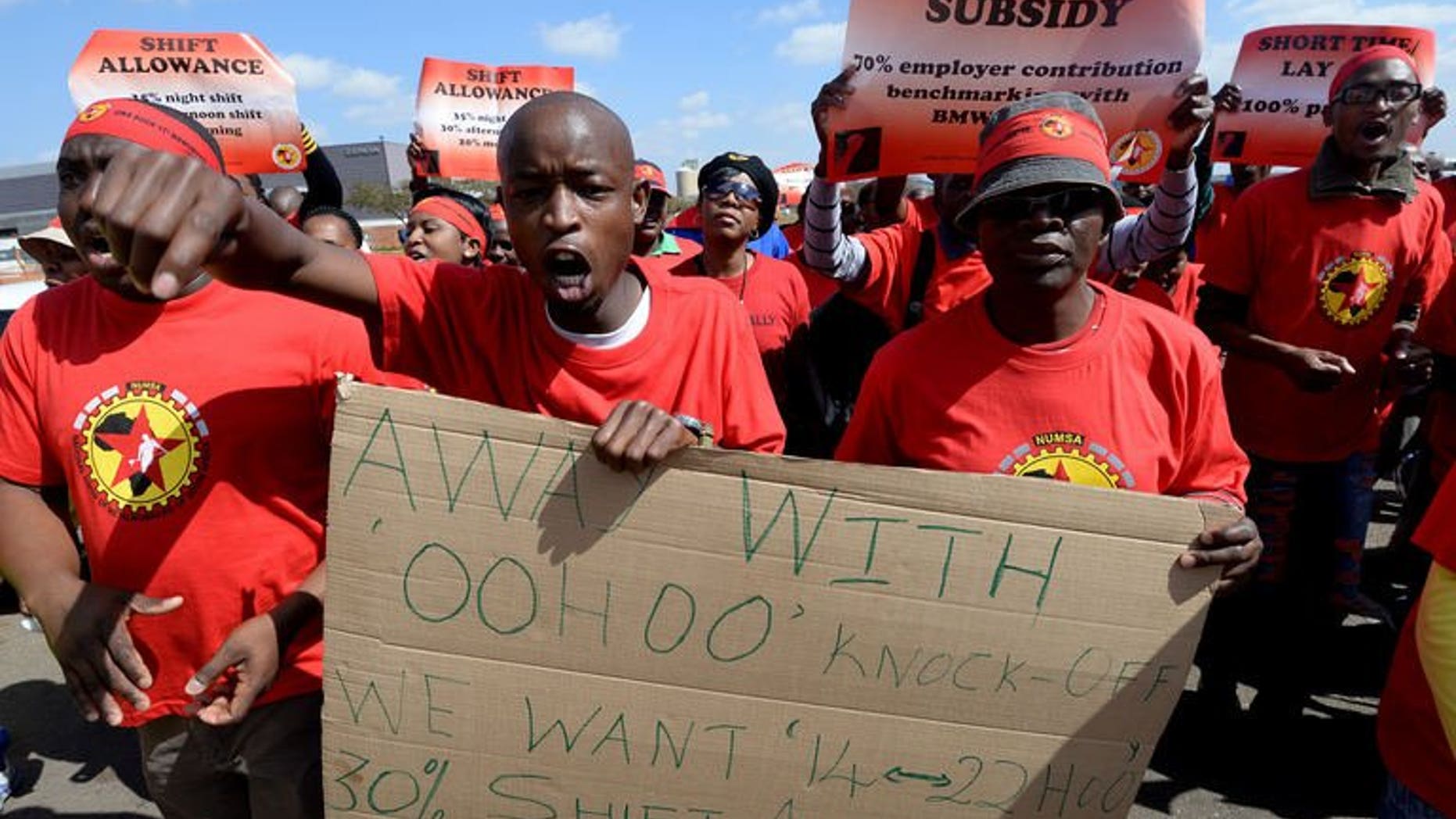 Workers on strike hold signs as they take part in a demonstration outside Ford's plant in Pretoria on August 20, 2013. A striking South African auto workers union will meet manufacturers on Thursday in a bid to break a wage deadlock that has crippled a multi-billion dollar export market.