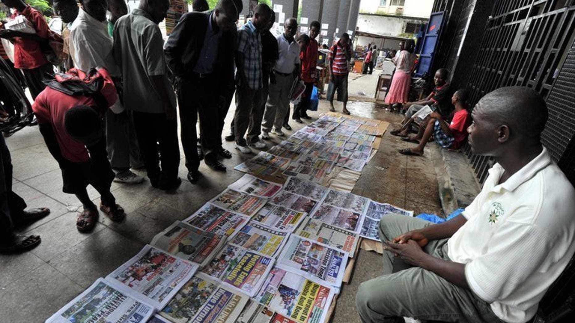 People look at newspapers laid out on the street in the Liberian capital Monrovia on October 12, 2011. The publisher of one of Liberia's leading local daily newspapers has been jailed for libel over a report about government corruption, according to an AFP correspondent at the court, sparking outrage in Monrovia.