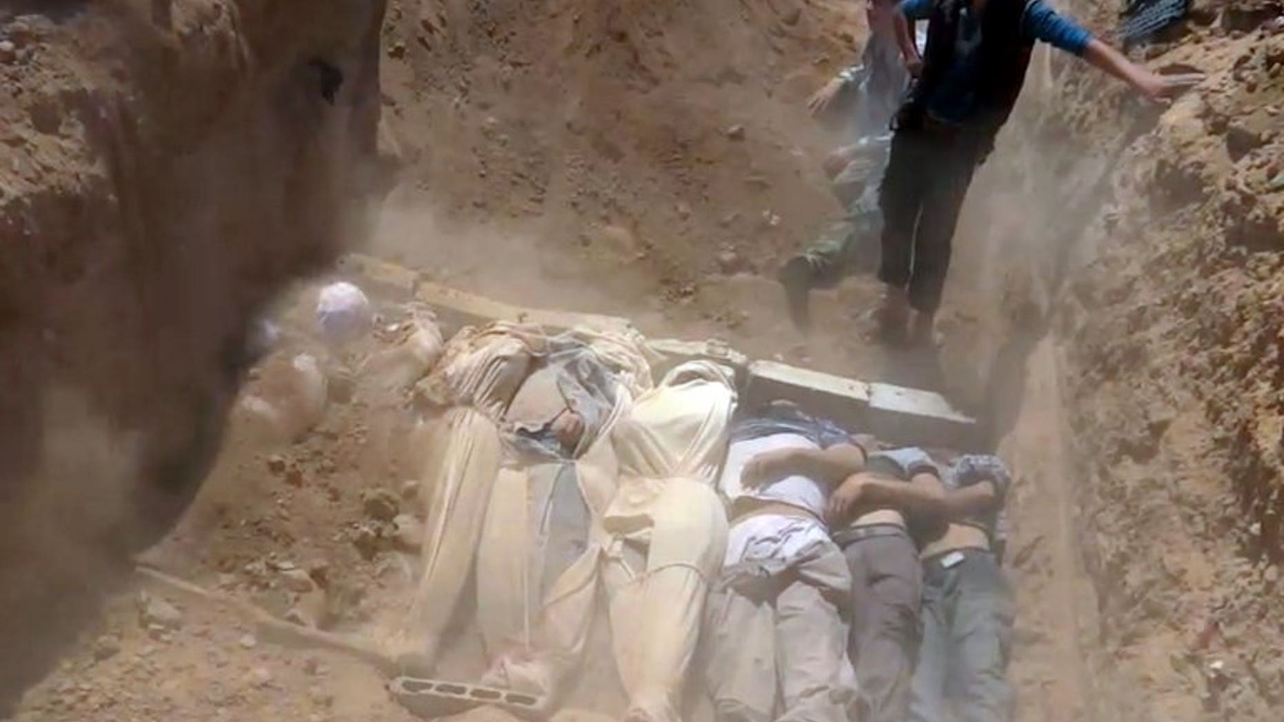An image grab taken from a video uploaded on YouTube by the Local Committee of Arbeen on August 21, 2013 allegedly shows Syrians covering a mass grave with bodies of victims of a toxic gas attack. The convulsions, pinpoint pupils and laboured breathing seen in victims of the alleged chemical attack could be symptoms of nerve gas, experts say, but only blood and urine samples can provide proof.