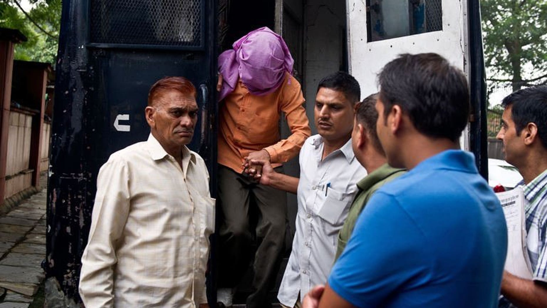 Indian policemen escort the juvenile accused (2nd L) in the December 2012 gang-rape of a student, from a police vehicle outside the juvenile court in New Delhi on August 19, 2013. The trials of five suspects for the fatal gang-rape of an Indian student on a bus last December moved towards their conclusions on Thursday, with the first verdict set for August 31.