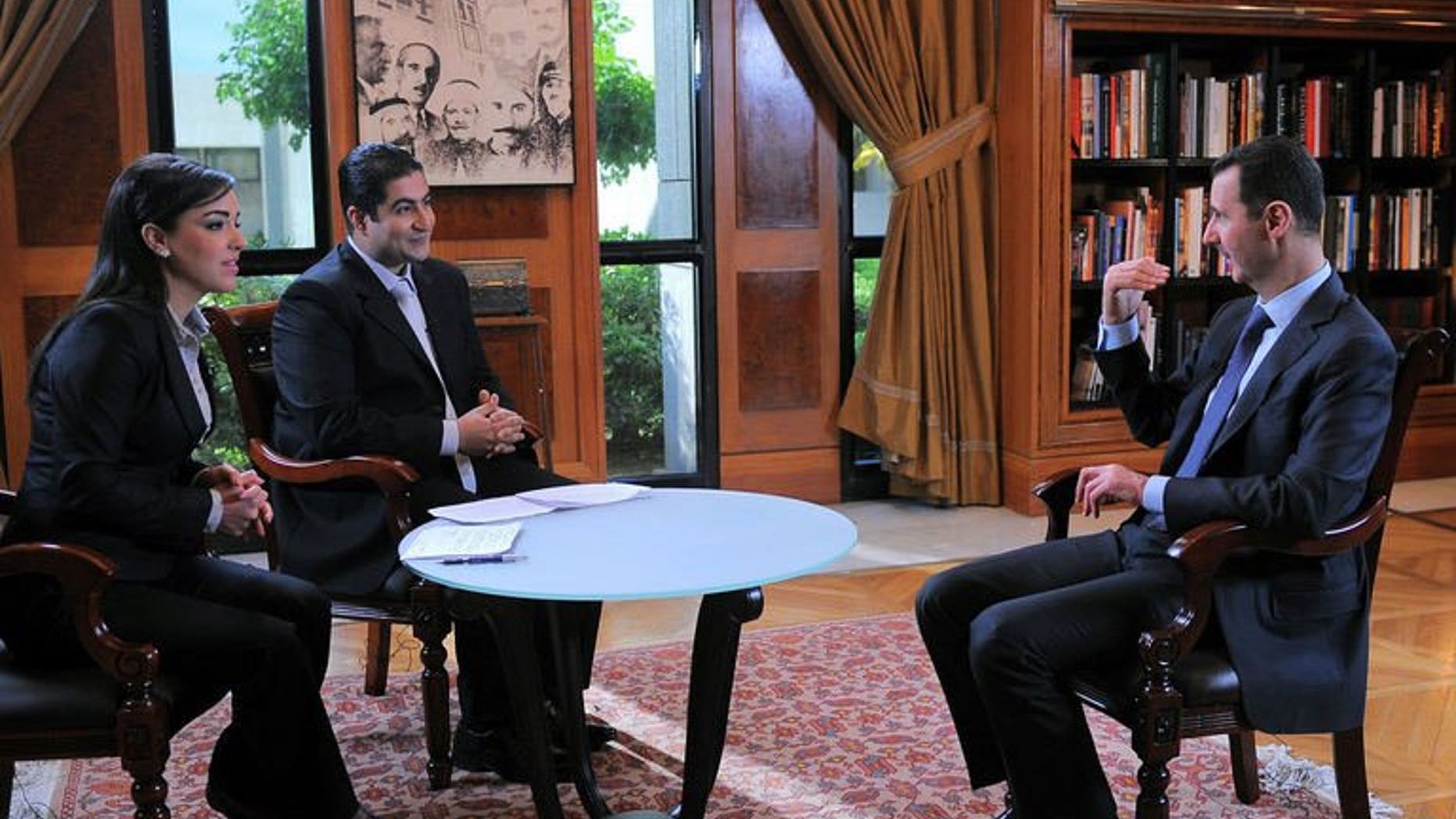 A handout picture from SANA on April 17, 2013 shows Syrian President Bashar al-Assad (R) during an interview in Damascus. Syrian President Bashar al-Assad appointed six new cabinet ministers on Thursday, the official SANA news agency reported, in a cabinet reshuffle targeting namely economic portfolios.