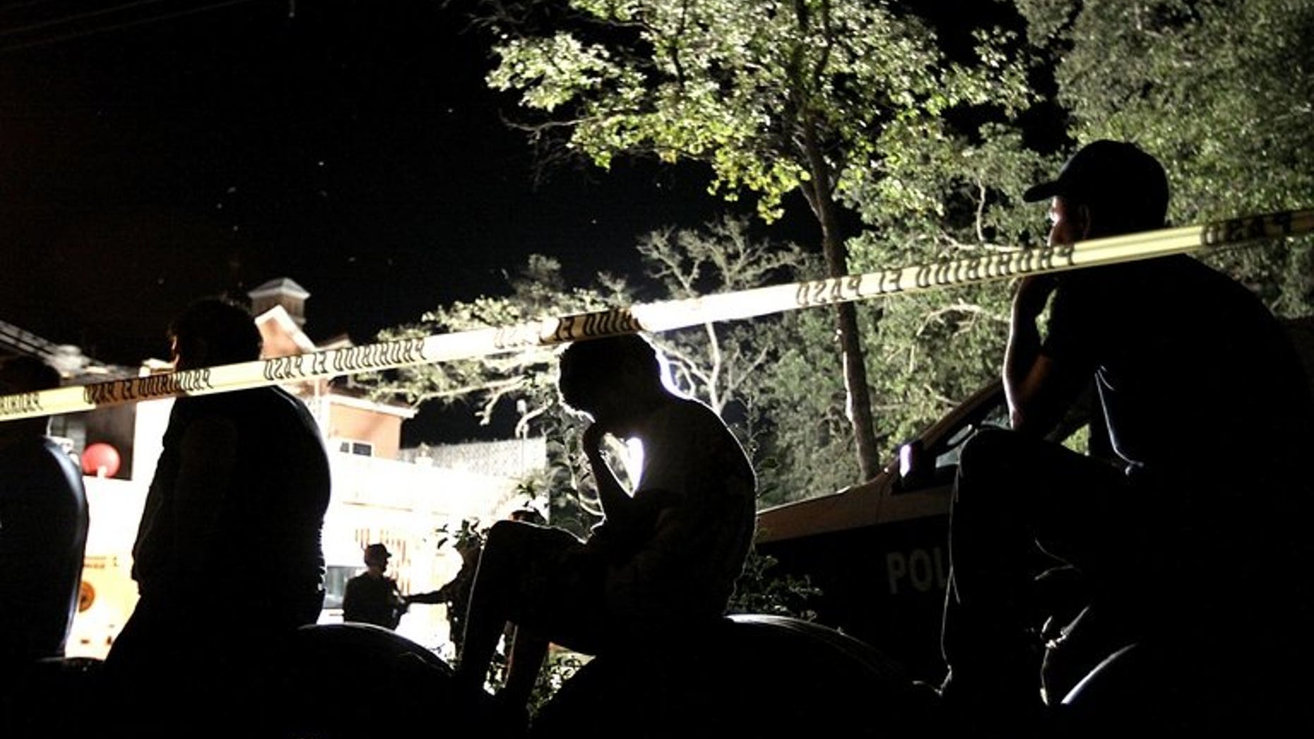 People observe police at a crime scene in Mexico on October 22, 2012. Mexican authorities are investigating whether human remains found in a park outside the capital belong to 12 young people whose kidnapping in May shocked the city, officials said Thursday.