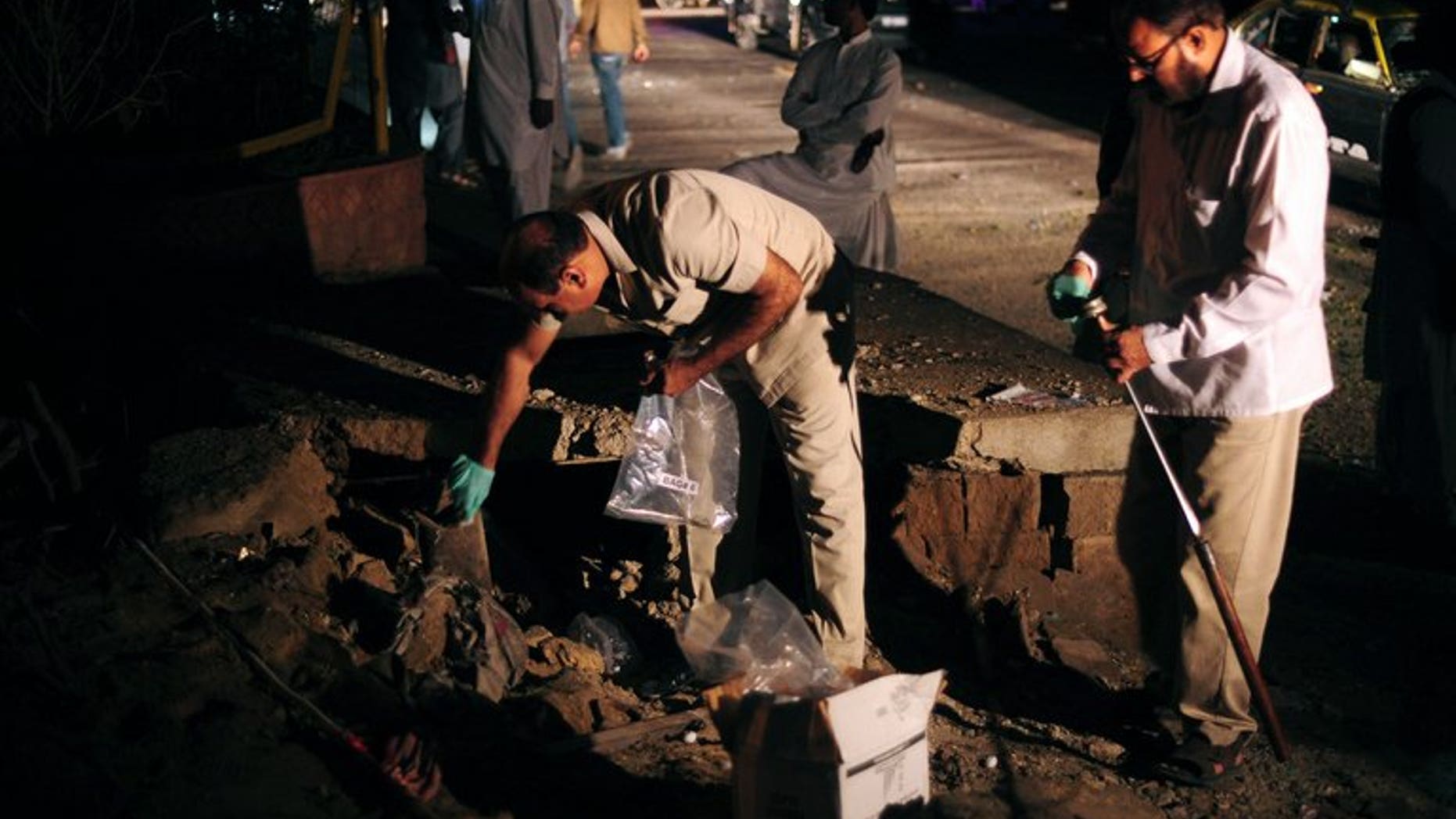 Pakistani security officials collect evidence at the site of a bomb explosion in Karachi on August 22, 2013. The death toll rose to two after a wounded soldier died.