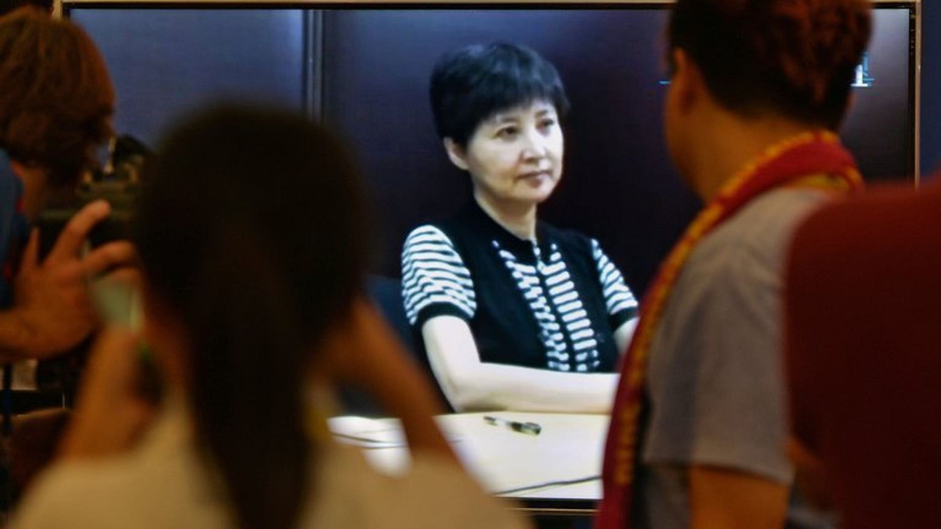 Journalists look at a broadcast of Gu Kailai (C), who is the wife of disgraced politician Bo Xilai, as she gives recorded testimony during his trial at the Intermediate People's Court in Jinan, Shandong Province on August 23, 2013. Fallen Chinese politician Bo Xilai described his wife as "insane" Friday after his corruption trial heard video testimony from her implicating him in bribery.