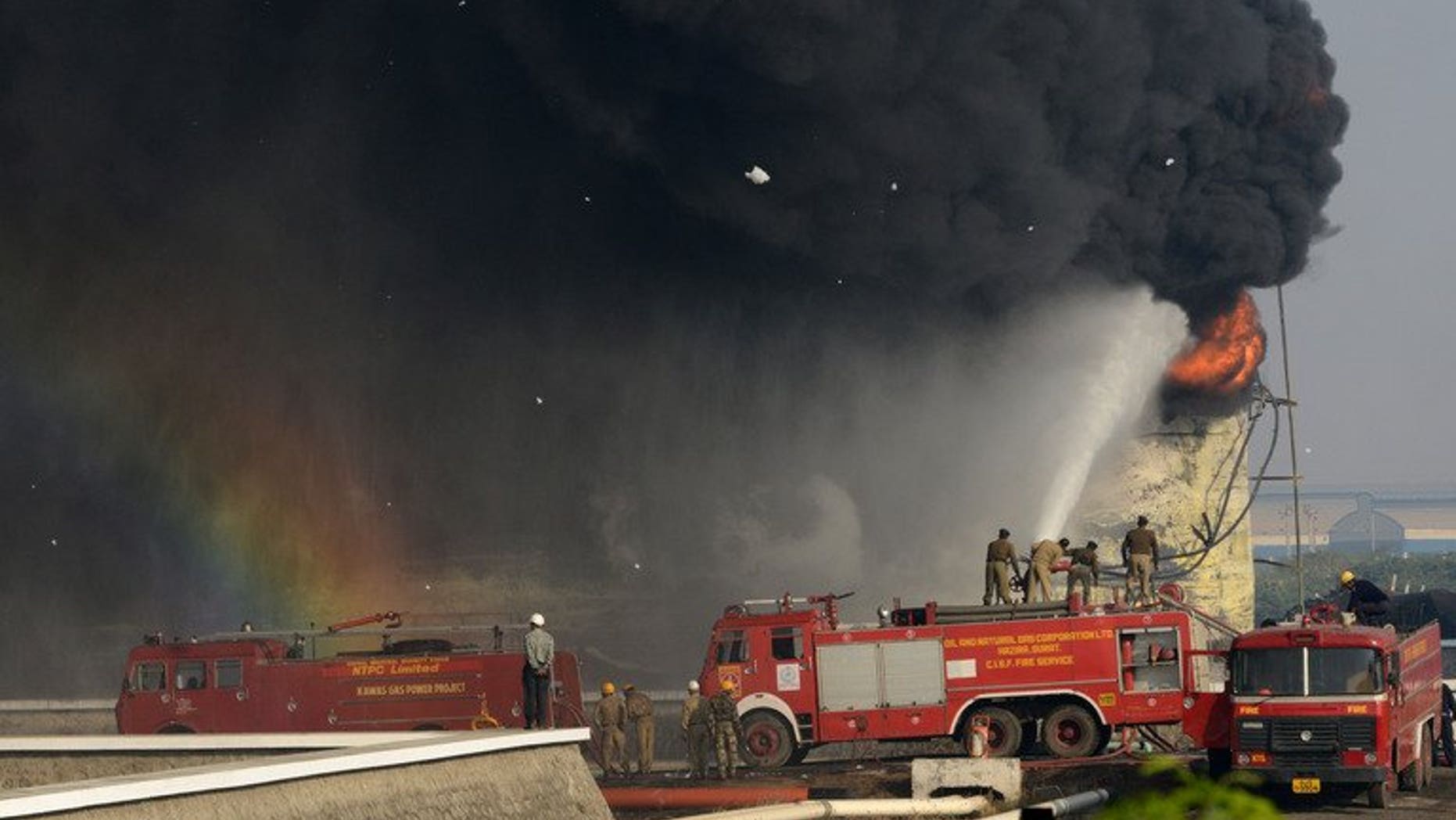 Indian firefighters battle to douse the flames of a burning fuel tank at the Indian Oil Corporation plant at Hajira near Surat, some 275 kms from Ahmedabad, on January 6, 2013. A massive fire broke out Friday at a petroleum refinery in southern India, killing four workers and leaving dozens injured, police said.
