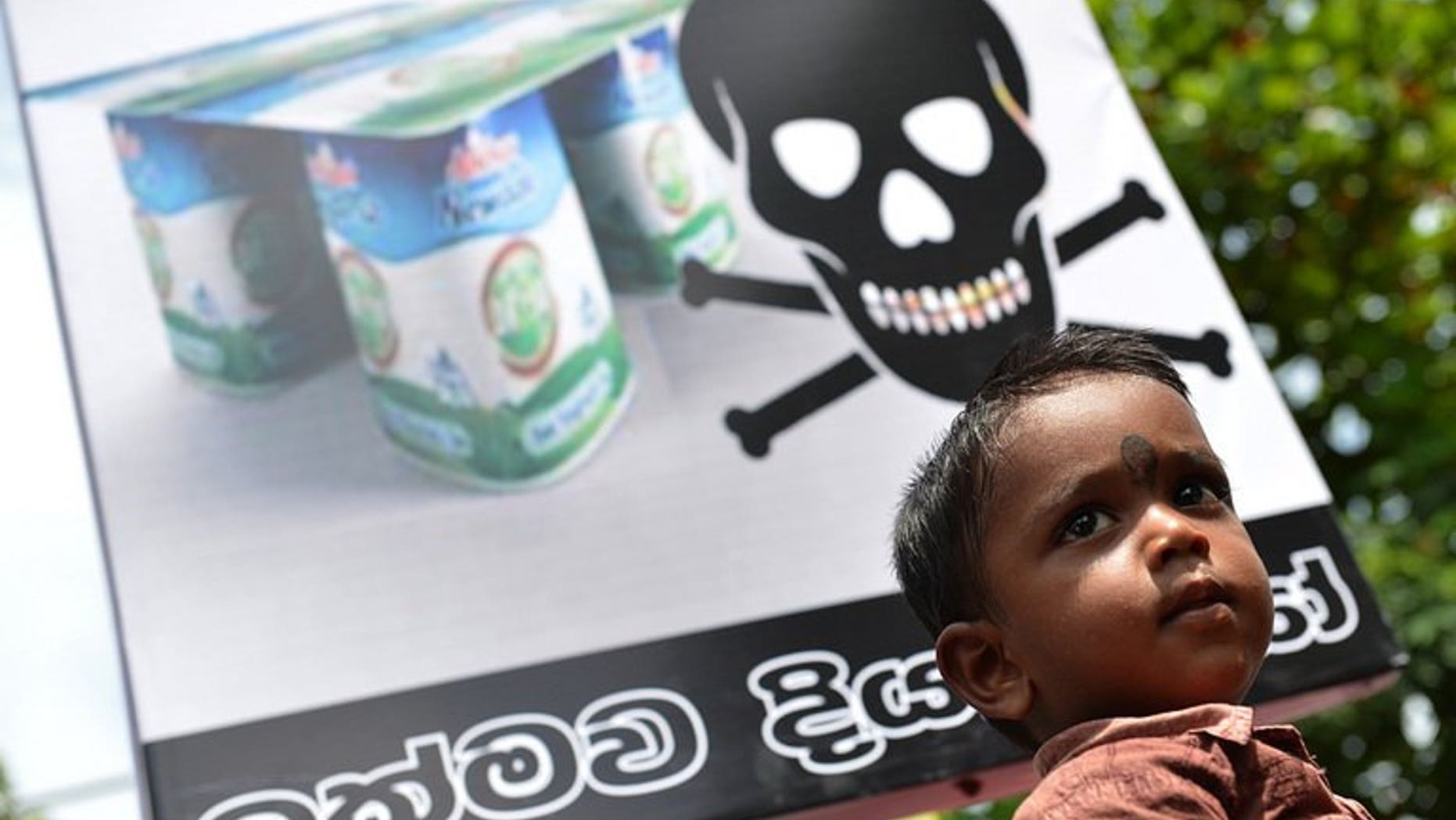 A Sri Lankan child looks on as pro-government activists protest the alleged contamination of milk powder outside the factory of dairy giant Fonterra in a Colombo suburb on August 22, 2013.