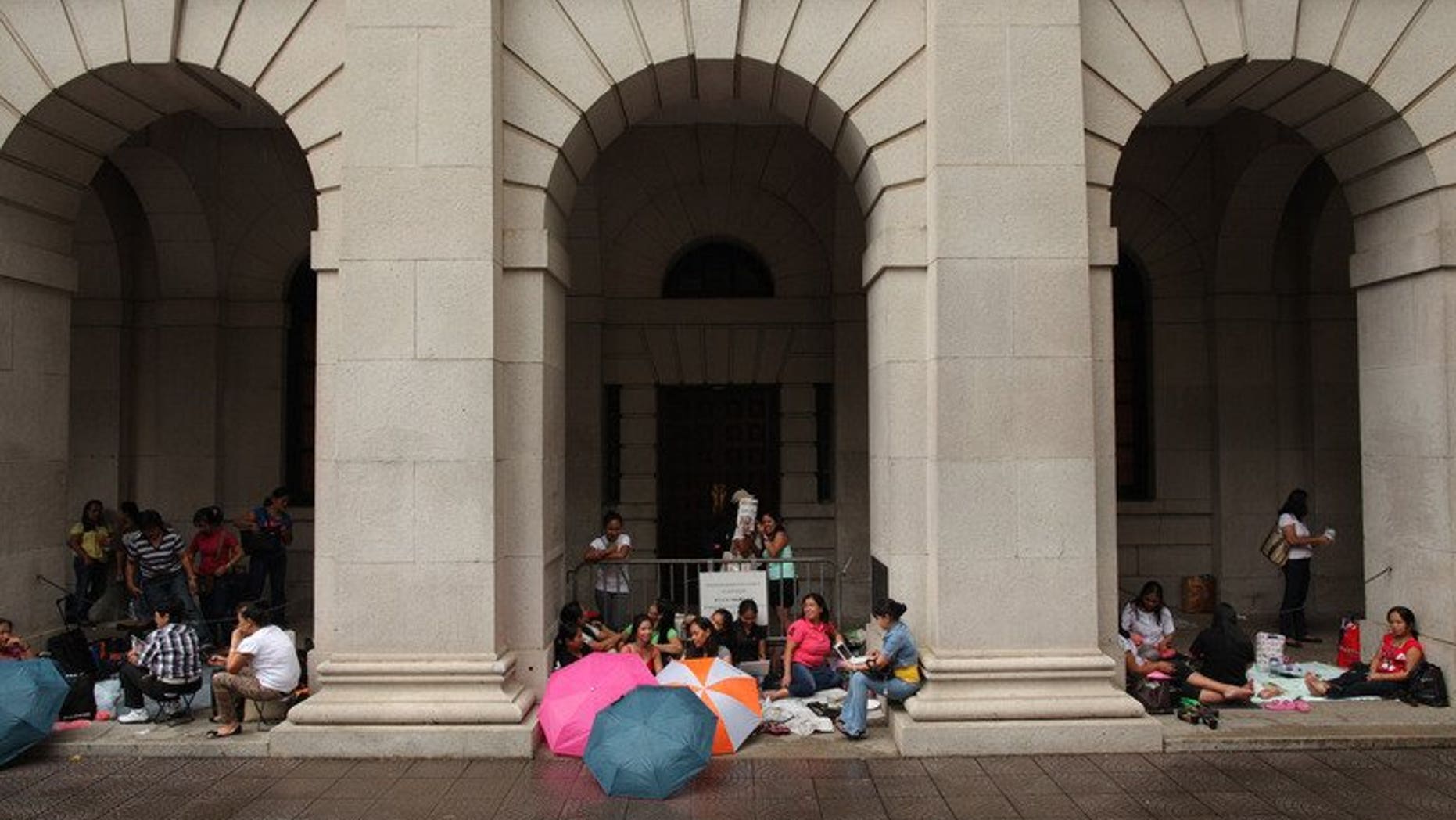 Foreign domestic helpers sit beneath the arches of the former Legislative Council building in Hong Kong on October 2, 2011. A Hong Kong couple left their Indonesian domestic helper without food or water after tying her to a chair and forcing her to wear a diaper while they went on five-day vacation, a report said Saturday.