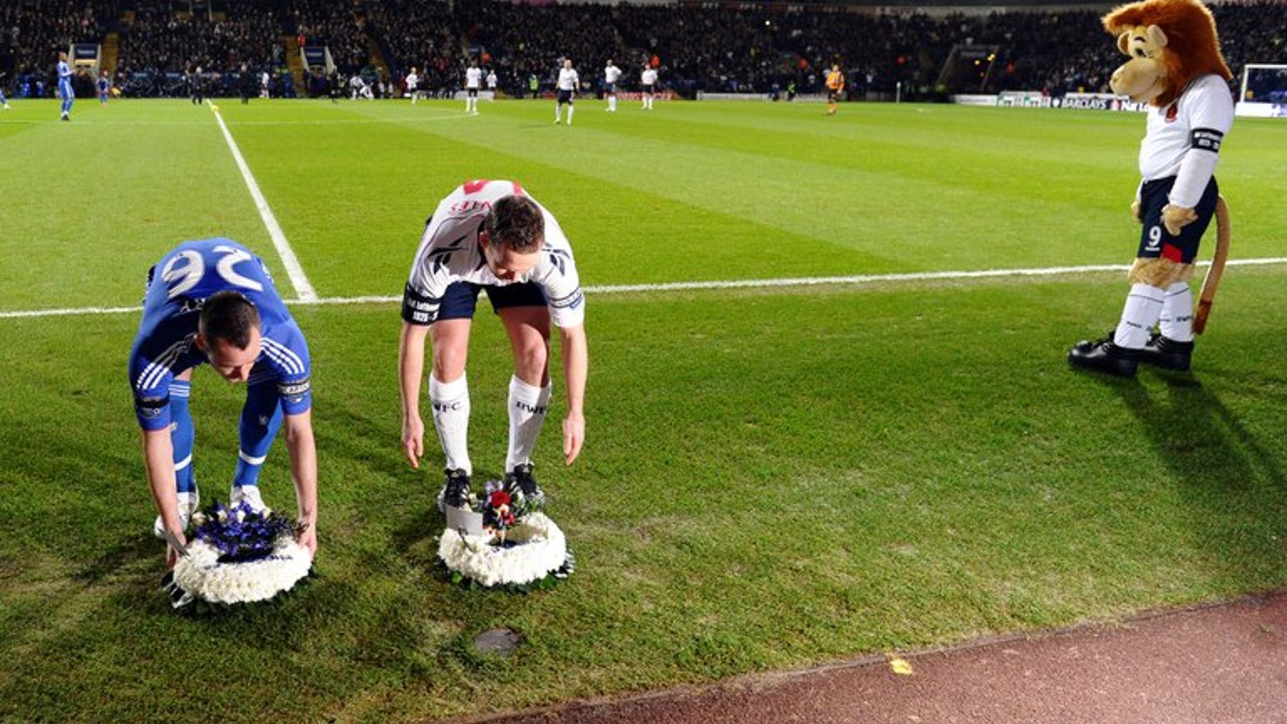 Bolton Wanderers mascot watches as Chelsea captain John Terry (left) and Bolton Wanderers captain Kevin Davies place wreaths by the side of the pitch following the death of former Bolton and England footballer Nat Lofthouse at The Reebok Stadium in Bolton on January 24, 2011. The club unveiled a statue of Lofthouse, the former England striker on Saturday.