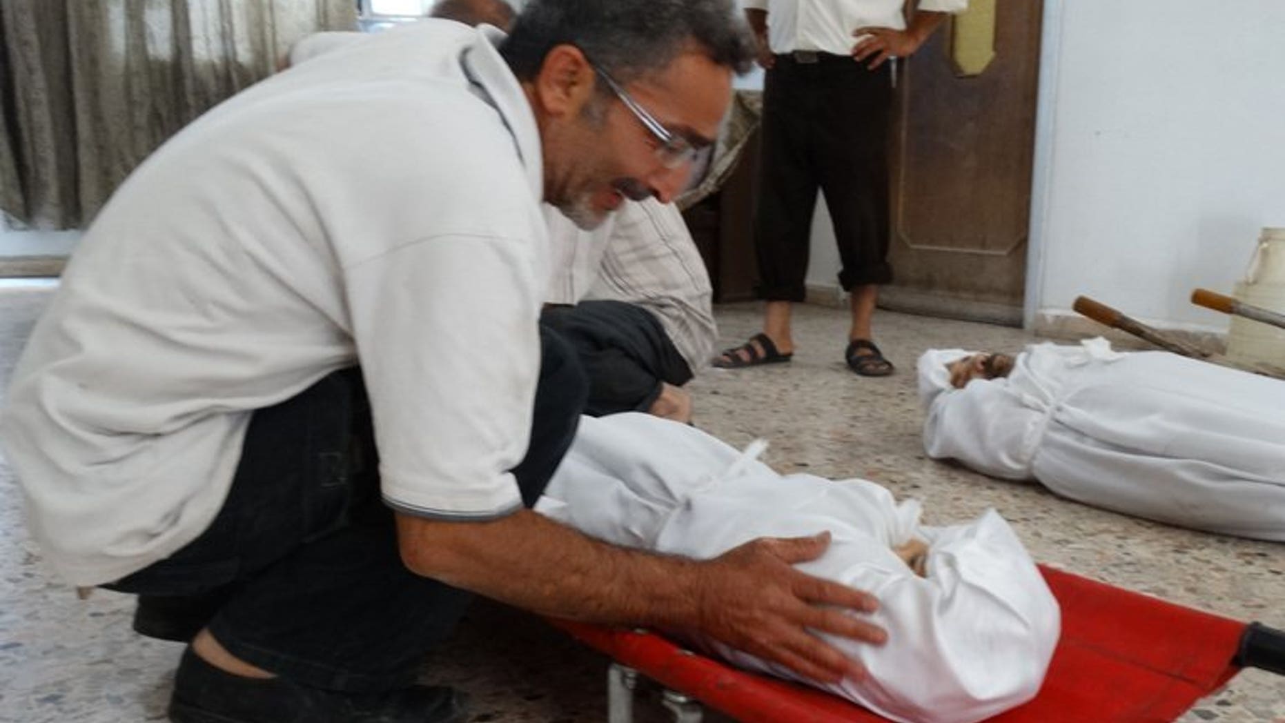 An image released by the Syrian opposition's Shaam News Network on August 23, 2013, shows a relative weeping over the body of an infant killed in an alleged toxic gas attack. Three Syrian hospitals have received around 3,600 patients displaying "neurotoxic symptoms", 355 of whom have died, Doctors without Borders (MSF) say.