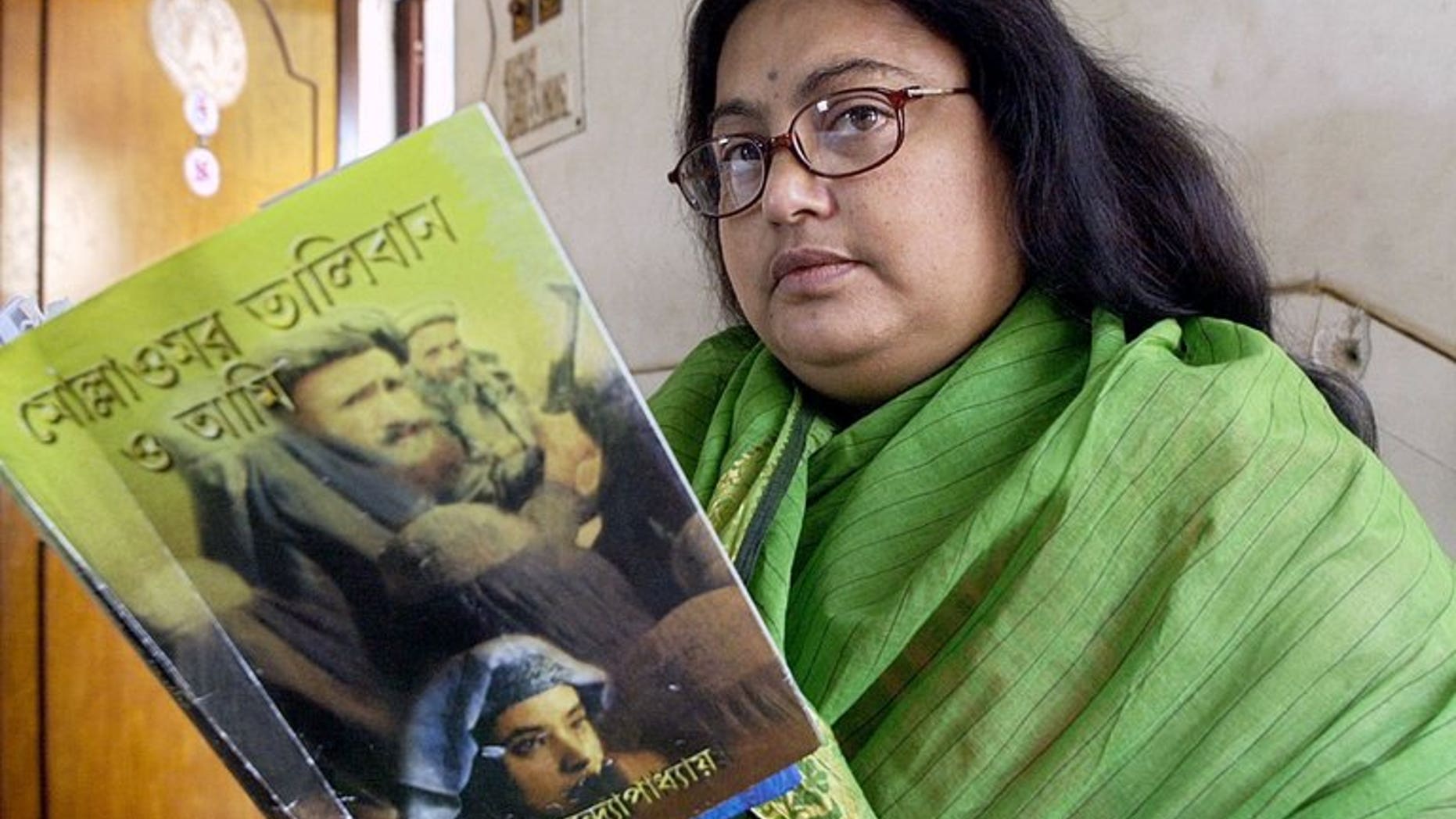 In this photograph taken on March 6, 2003, Indian author Sushmita Banerjee holds one of her Bengali language novels "Mollah Omar Taliban O Aami" (Mollah Omar, Taliban and Me) in Kolkata. Suspected Taliban militants have shot dead Banerjee in the eastern Afghan province of Paktika, police said.