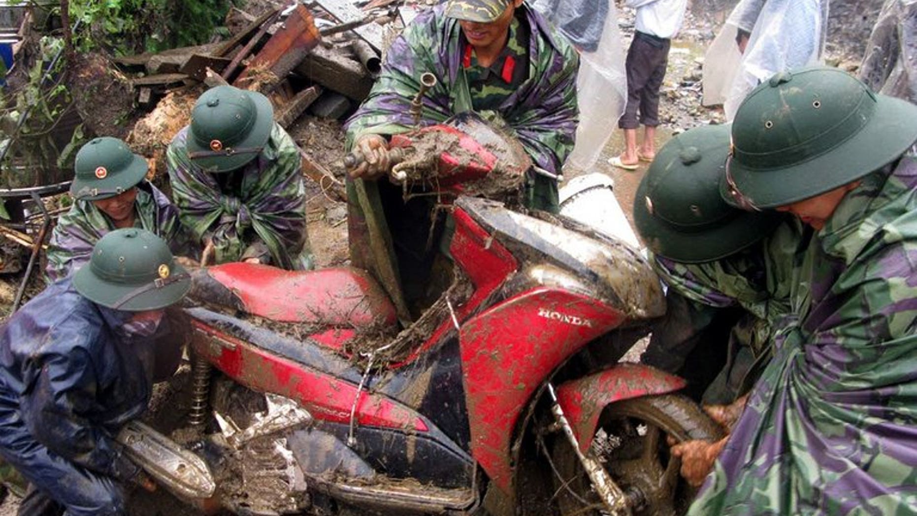 This photo, taken by the Vietnam News Agency on September 5, 2013, shows soldiers pulling out a motorcycle from debris at the scene of flash floods in Sapa district, northern province of Lao Cai. At least 21 people have been killed as flash floods and landslides ravaged mountainous areas in northern Vietnam.