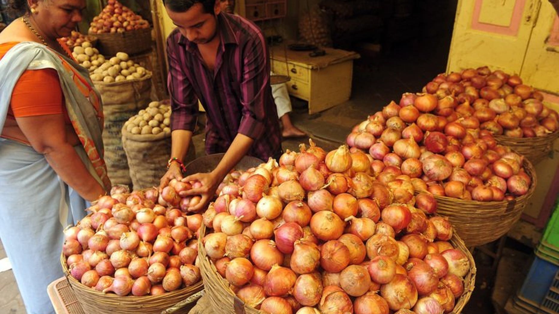 A customer looks on as a shop assistant selects onions for her at a market in Mumbai on August 22, 2013. A US-based website offering onions at heavily discounted prices in India has seen an "overwhelming" response as consumers there reel from sky-rocketing prices of the vegetable.