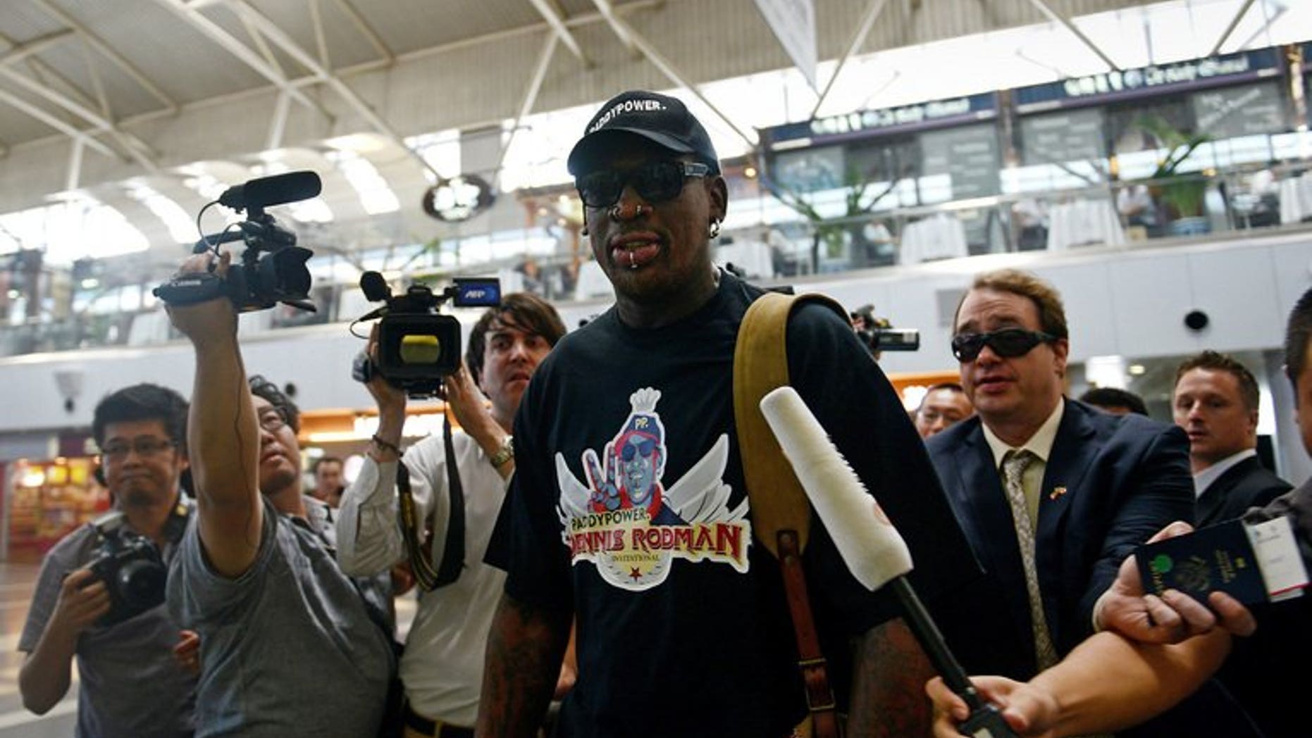 Former US NBA basketball player Dennis Rodman (C) is surrounded by members of the media as he makes his way through Beijing's international airport on September 3, 2013.