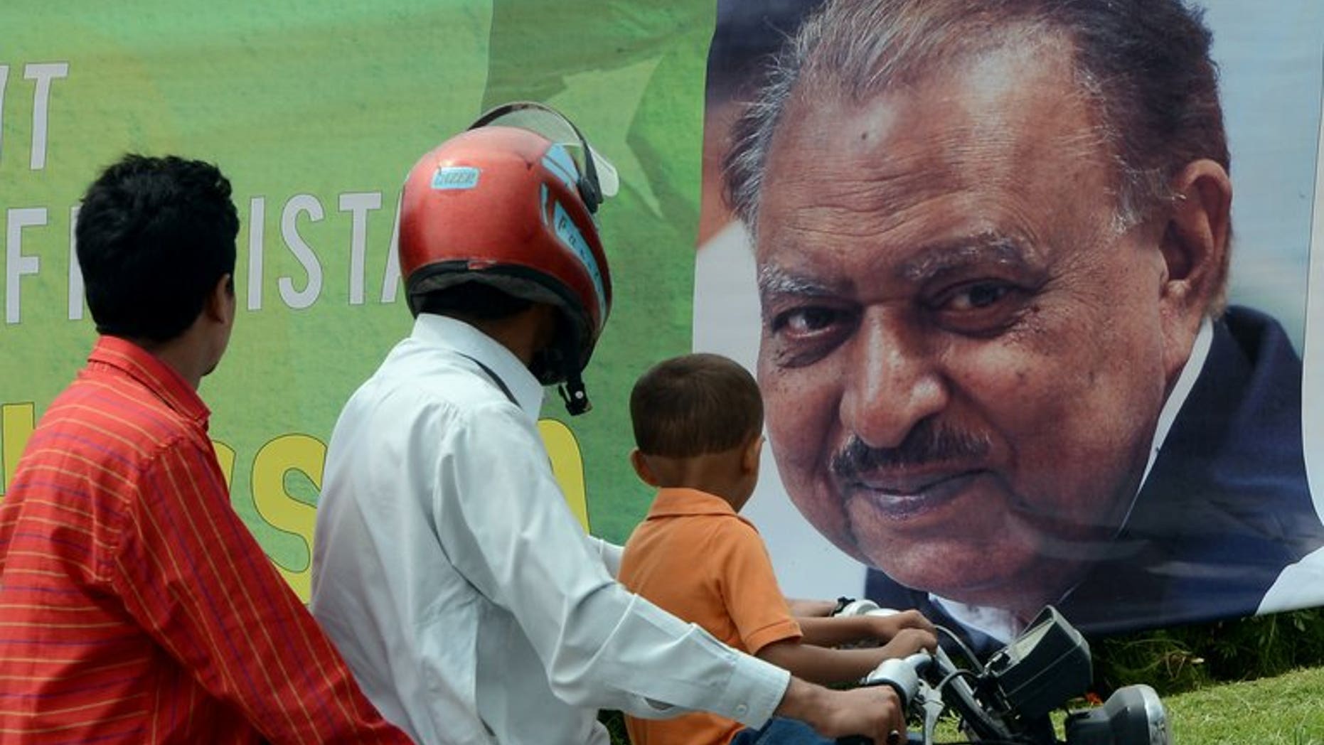 Commuters pictured in front of a roadside banner welcoming and congratulating incoming Pakistani President Mamnoon Hussain in Islamabad on September 9, 2013. He took office on Monday, presiding over a government battling to overcome a Taliban insurgency, resolve an energy crisis and repair the economy.