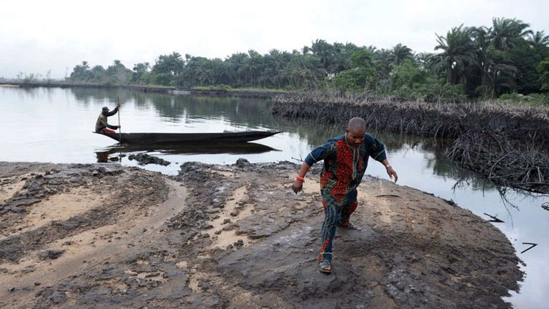 A man walks on slippery spilled crude oil on the shores of the Niger Delta swamps of Bodo on June 24, 2010.