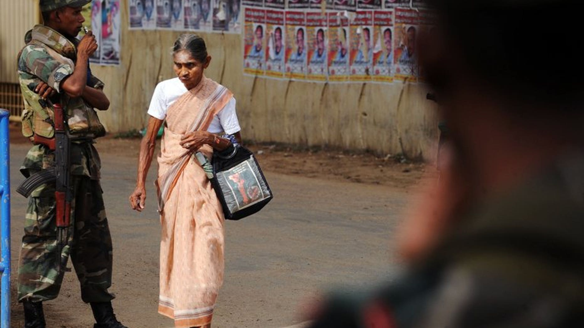 An elderly Sri Lanka woman walks past armed soldiers in the northern town of Jaffna on April 30, 2010. Sri Lanka's main Tamil party Tuesday demanded troops be confined to barracks after accusing them of campaigning for the ruling party at key elections in the former separatist stronghold of Jaffna.