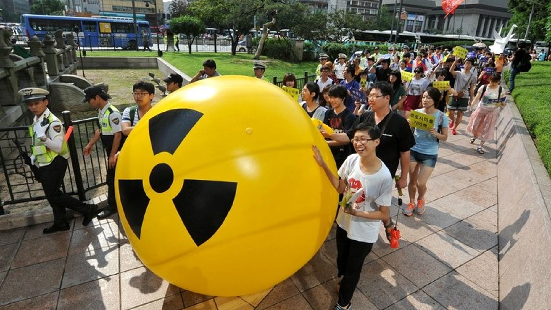 South Korean activists march while rolling a large balloon with a radioactivity warning sign during an anti-nuclear protest in Seoul on August 6, 2013. A former deputy minister has been charged with taking bribes as part of a corruption probe into South Korea's nuclear industry which has already indicted nearly 100 people, prosecutors said Tuesday.