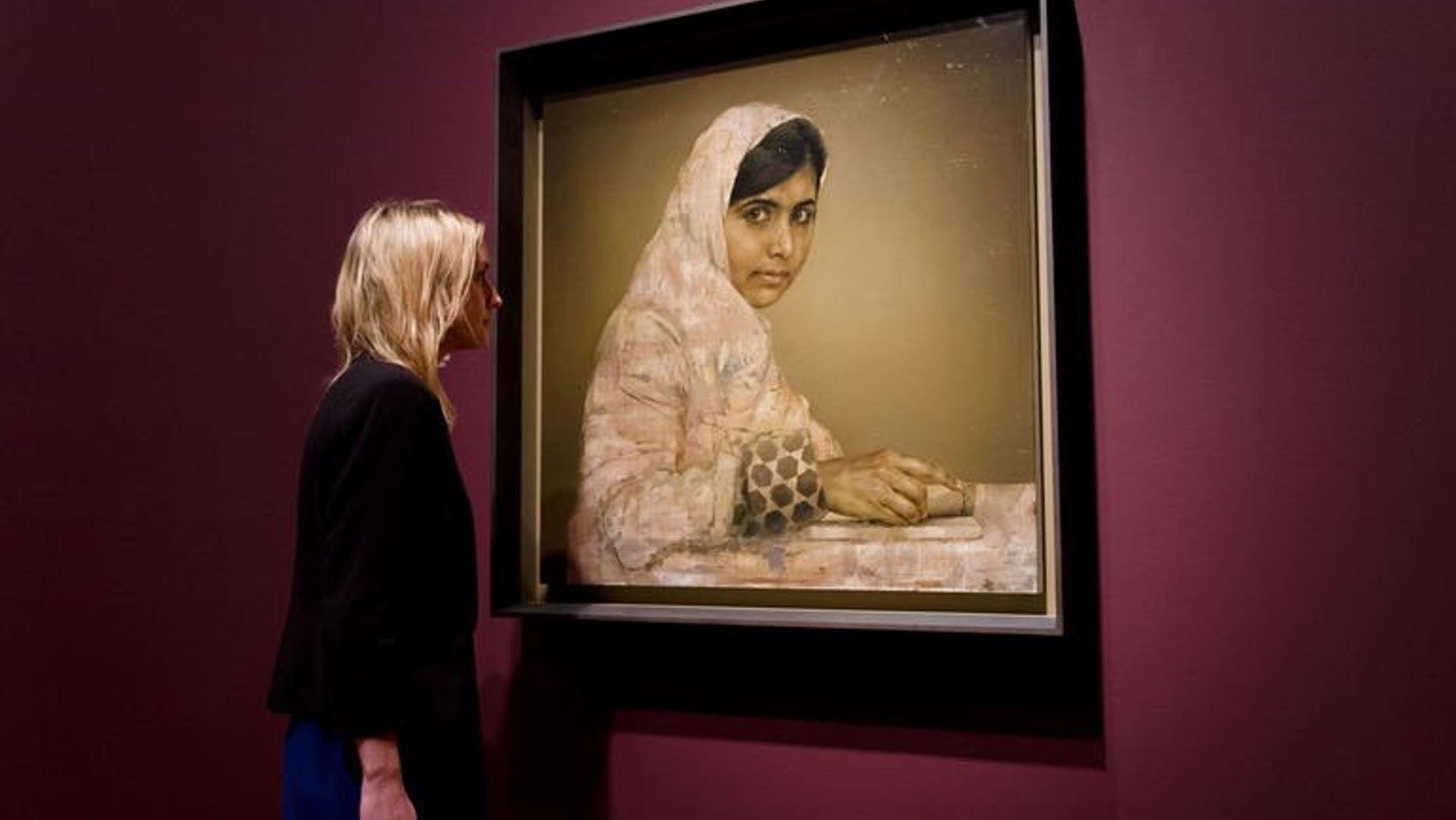 A gallery worker poses with a painted portrait of Malala Yousafzai, the teenage Pakistani advocate for girls education who was shot in the head by the Taliban in 2012, by Jonathan Yeo at the National Portrait Gallery in central London on September 10, 2013.