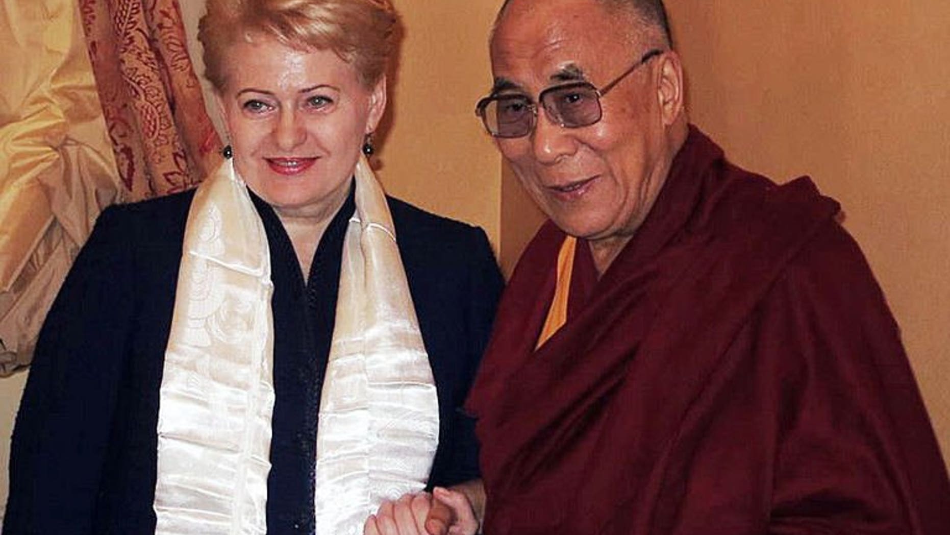 This handout released by the Press service of the President of Lithuania shows Lithuanian President Dalia Grybauskaite (L) shaking hands during a private meeting with exiled Tibetan spiritual leader the Dalai Lama in Vilnius on September 11, 2013.