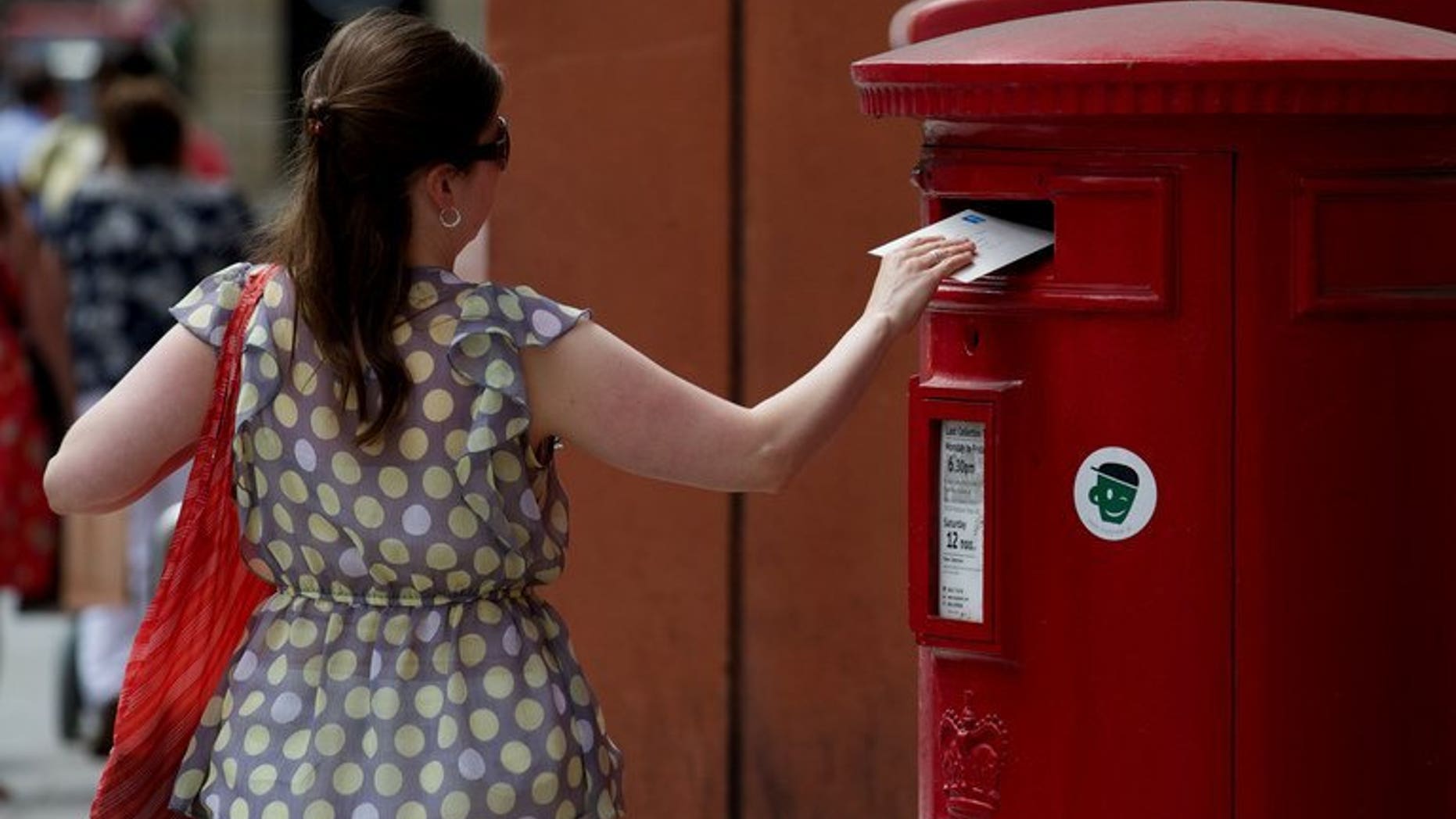 A woman posts a letter in a Royal Mail post box in London on July 10, 2013. Britain's government announced plans to privatise more than half of Royal Mail, the state-run postal delivery service, following a major restructuring in recent years triggered by a surge in email use.