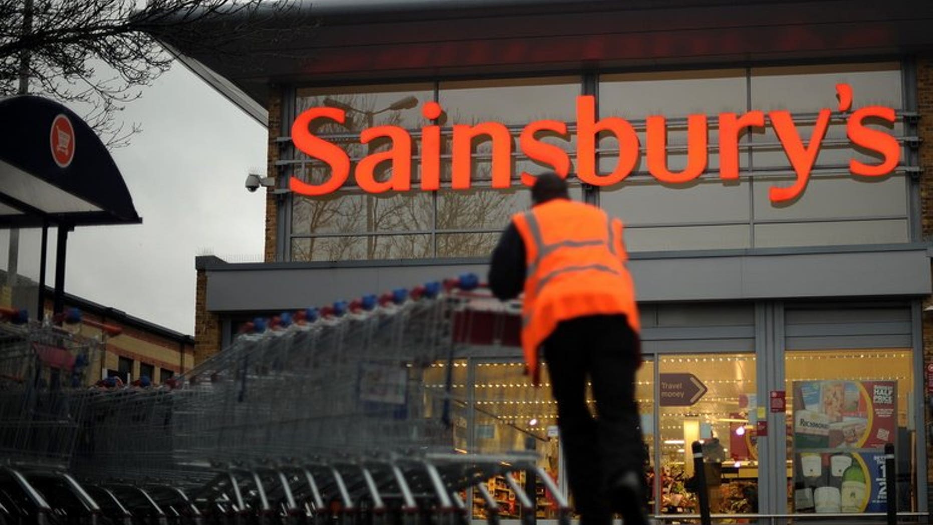 An employee moves shopping trolleys in front of a Sainsbury's store in London, on January 12, 2011. Sainsbury's has issued a recall of all of its bagged watercress and salads containing watercress due to an outbreak of E. coli.