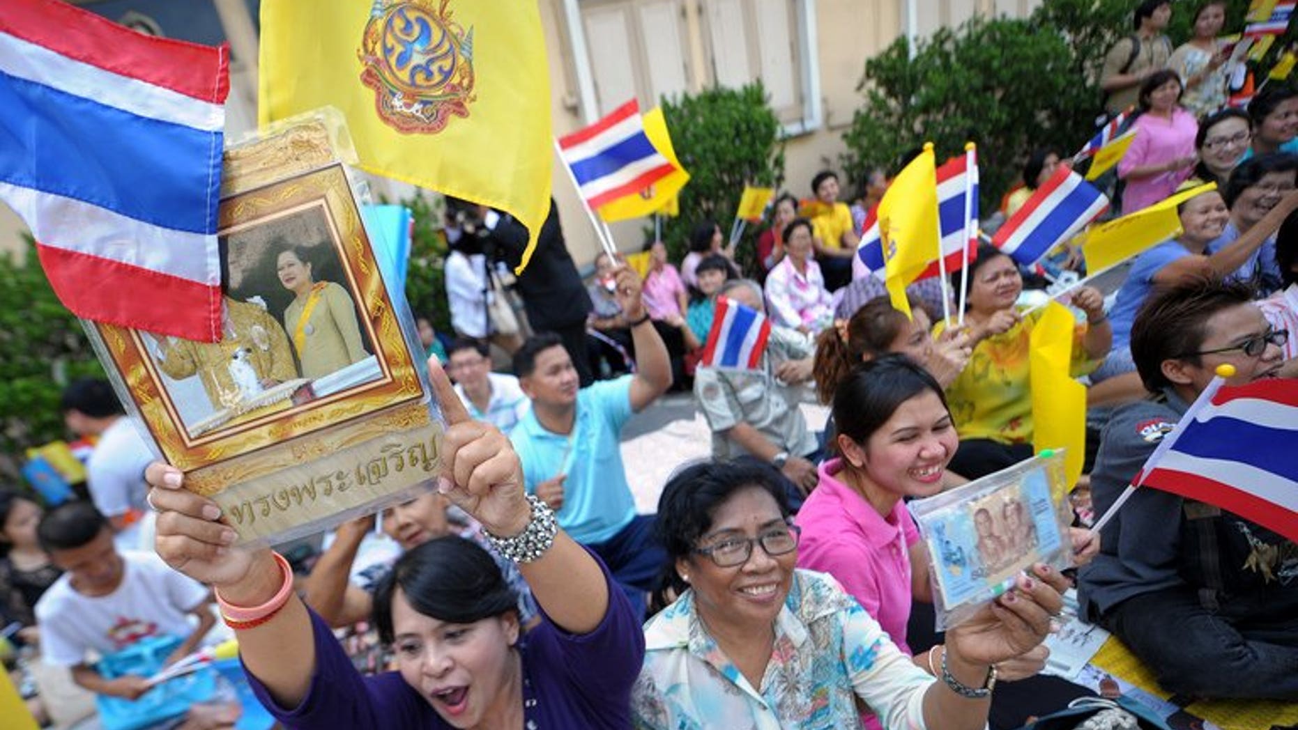 Well-wishers wave flags as they wait for Thai King Bhumibol Adulyadej to leave hospital in Bangkok on August 1, 2013. A Thai court on Friday acquitted a man held for nearly a year under royal defamation laws after his own brother accused him of insulting the king in their home.