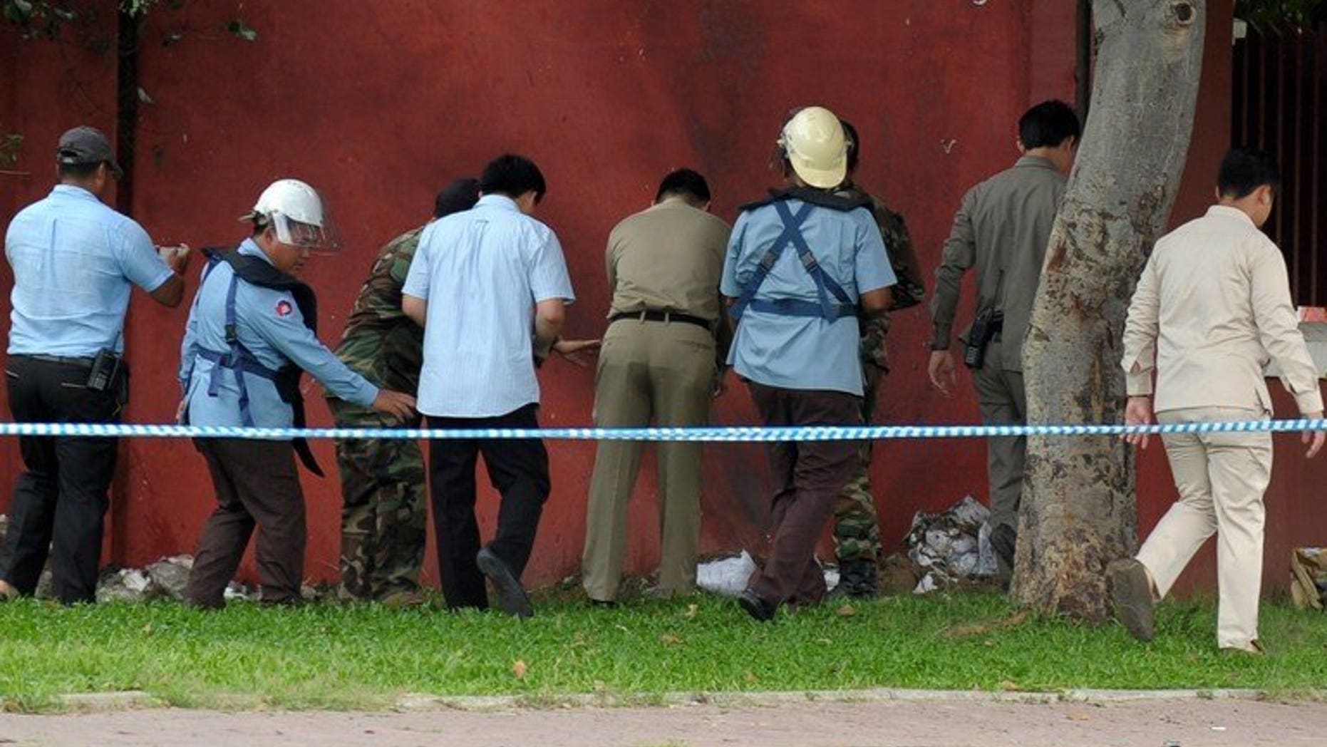 Bomb officials and police inspect a home-made bomb near Cambodia's parliament in Phnom Penh on September 13, 2013. The makeshift bomb was safely detonated by explosive experts, causing a loud bang that shook some nearby buildings, police said.