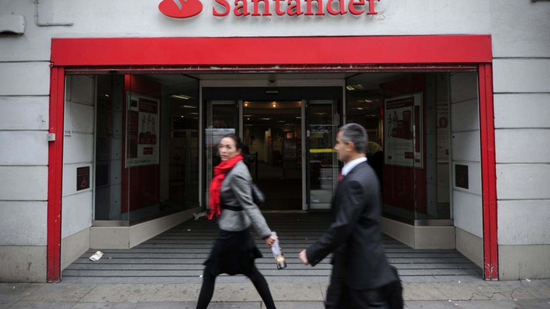 People walk past a branch of Santander in central London, on October 7, 2011. British police said Friday they have arrested 12 men over a "sophisticated" plot to remotely take control of a computer at a branch of Santander bank and steal millions of pounds.
