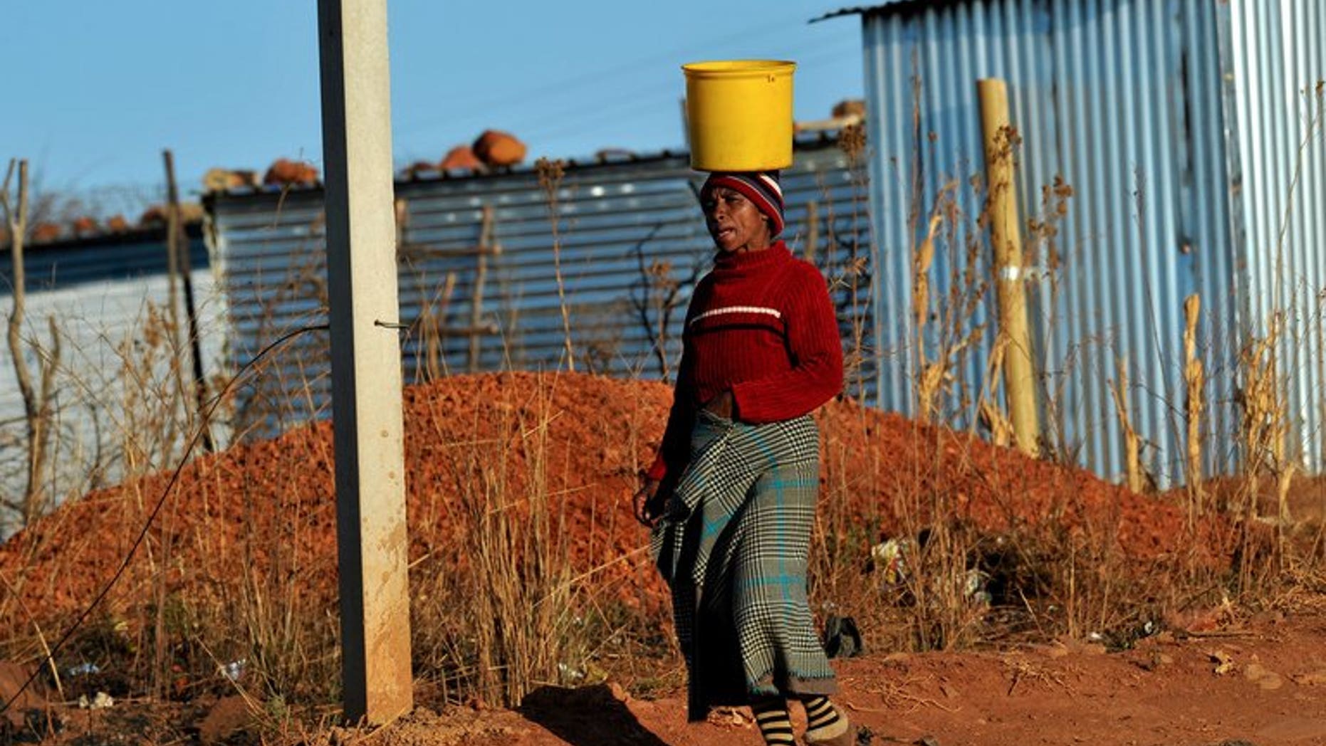 A woman brings water to her shack as workers who support the National Union of Mineworkers start a strike in Carletonville on September 3, 2013. South African construction workers have ended a three week strike after reaching a 12 percent wage hike deal with employers, their union said on Friday.