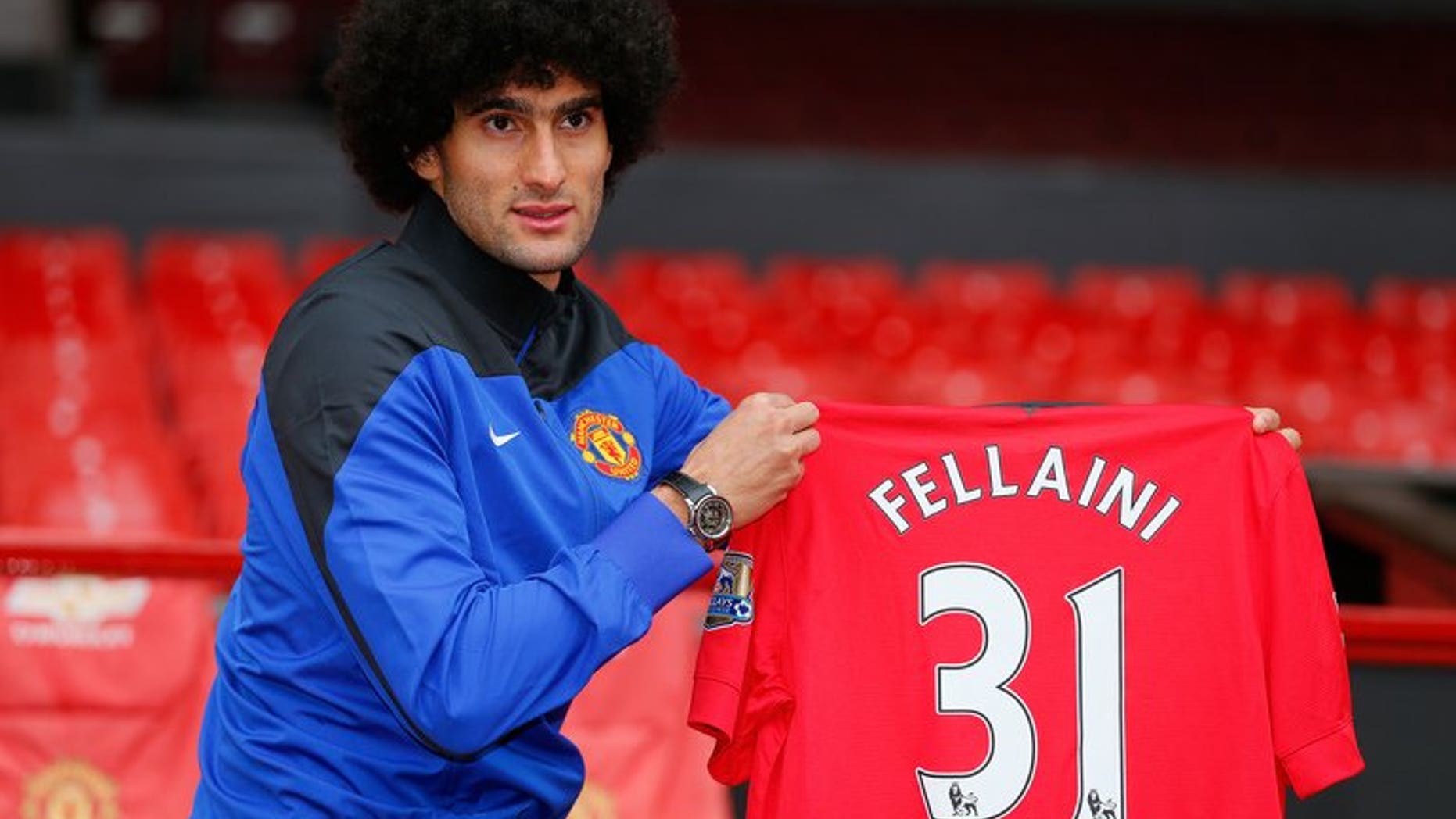 Manchester United's newly signed Belgian midfielder Marouane Fellaini poses with his shirt in Manchester, north-west England on September 13, 2013. Fellaini became Moyes first United signing for a fee of 27.5 million GBP (32.7 million Euros).