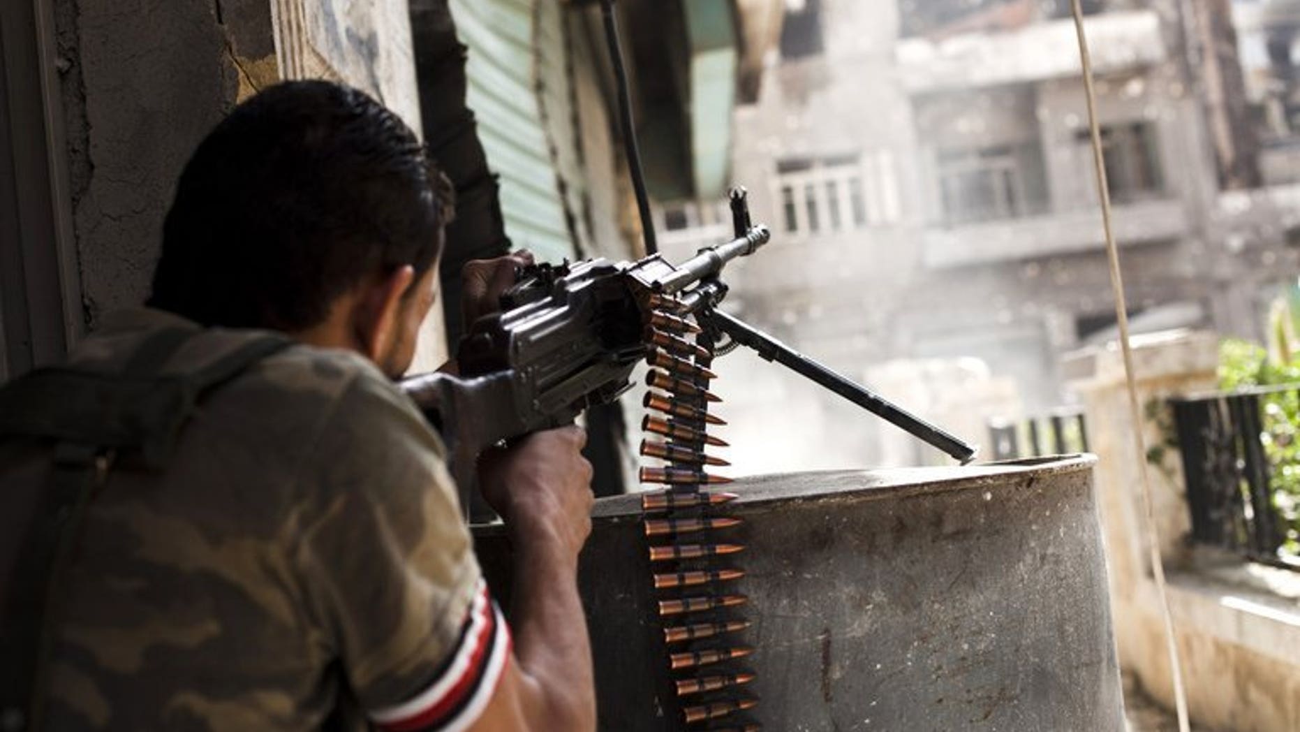 A Syrian rebel fighter fires his gun against a government troop position in the northern city of Aleppo, on October 21, 2012. British Foreign Secretary William Hague has welcomed a US-Russian deal to eliminate Syria's chemical weapons and said the priority now was the "full and prompt implementation" of the agreement.