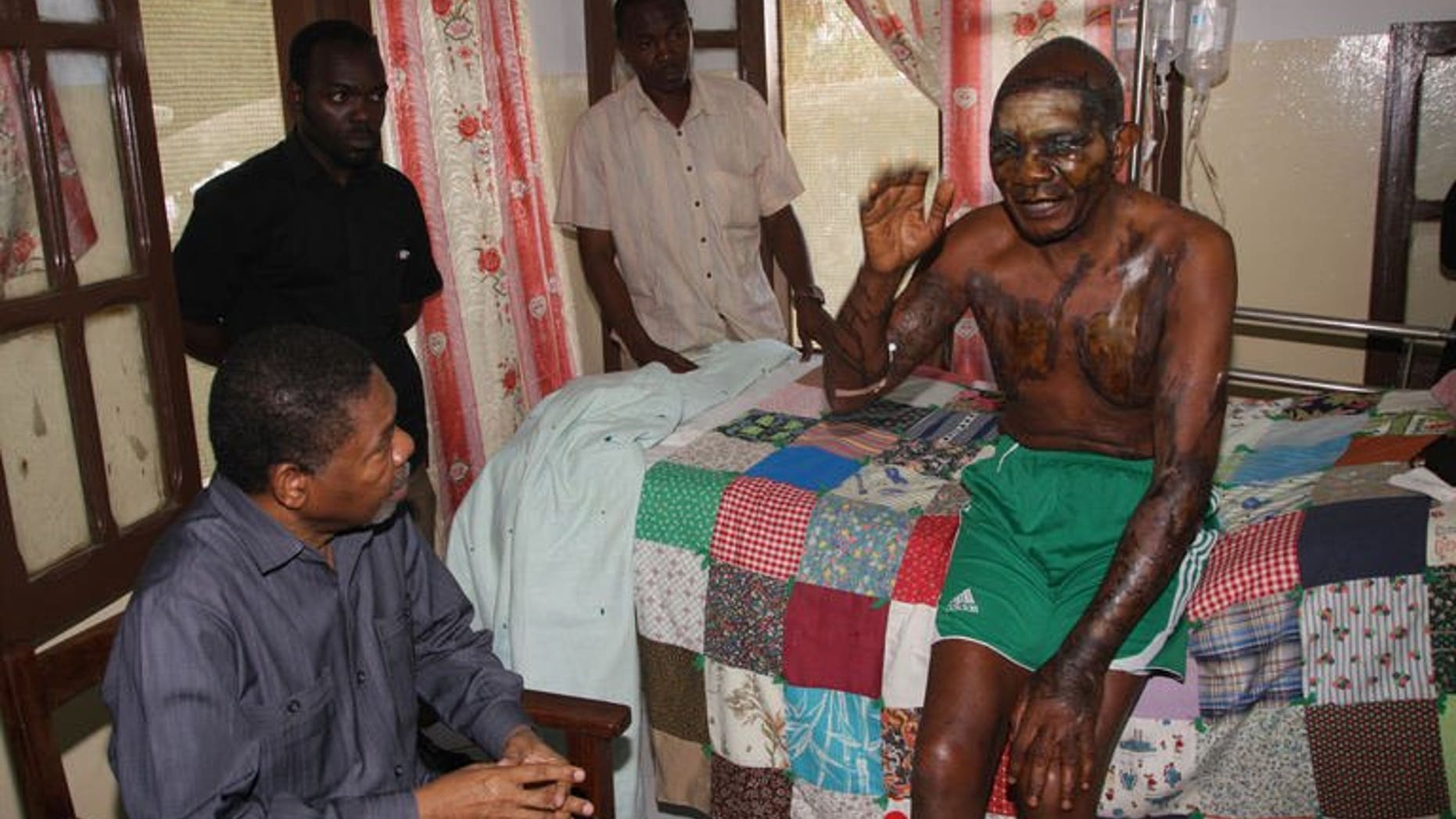 Zanzibar President Ali Mohamed Shein (Bottom L) consoles Roman Catholic priest Joseph Anselm Mwangamba (R) as he is treated at the Mnazi Mmoaj Hospital, Zanzibar's main hospital in the Stone Town, on September 14, 2013.