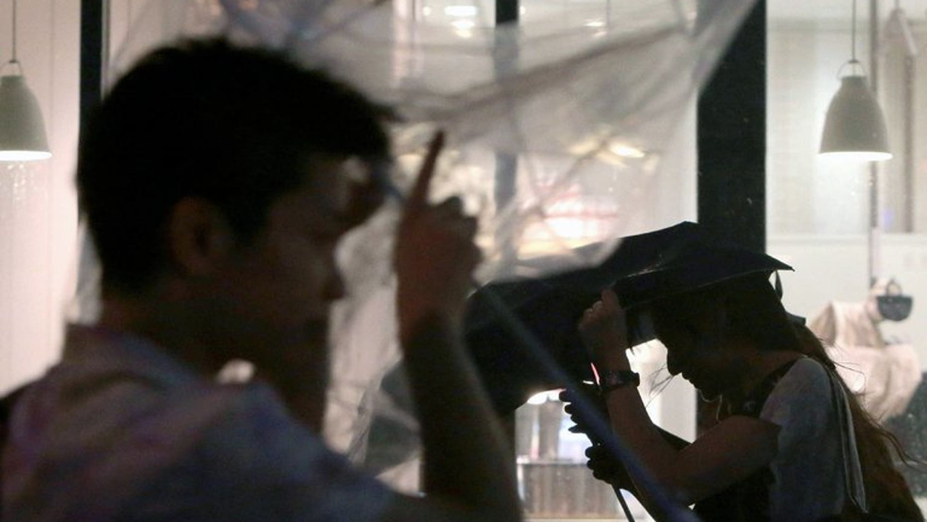 People try to hold on to their umbrellas during a typhoon in Tokyo on September 30, 2012.