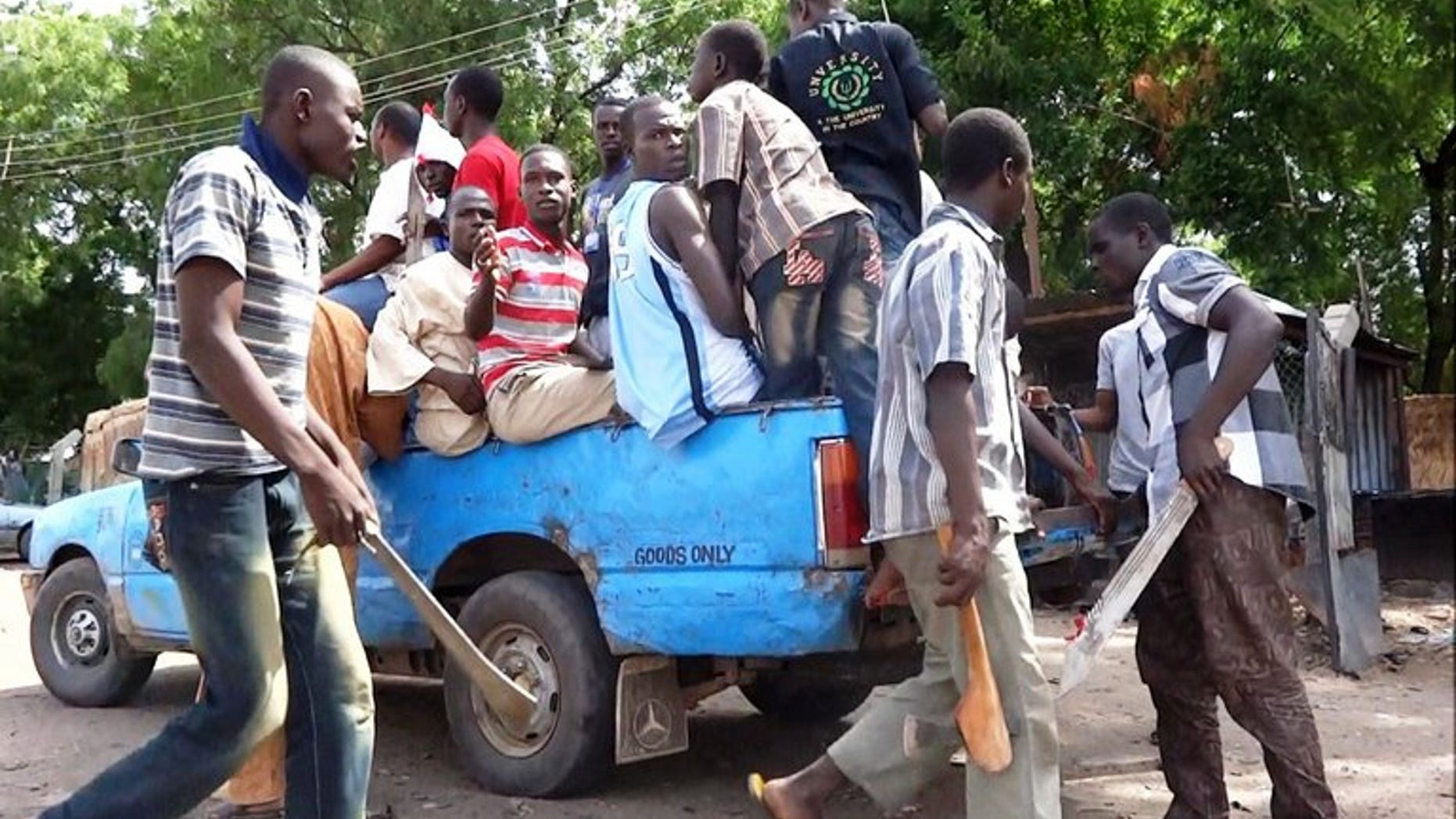 Machete and axe wielding neighbourhood vigilantes hop into a pick-up on July 19, 2013 for an operation to hunt down Boko Haram Islamists in Maiduguri.