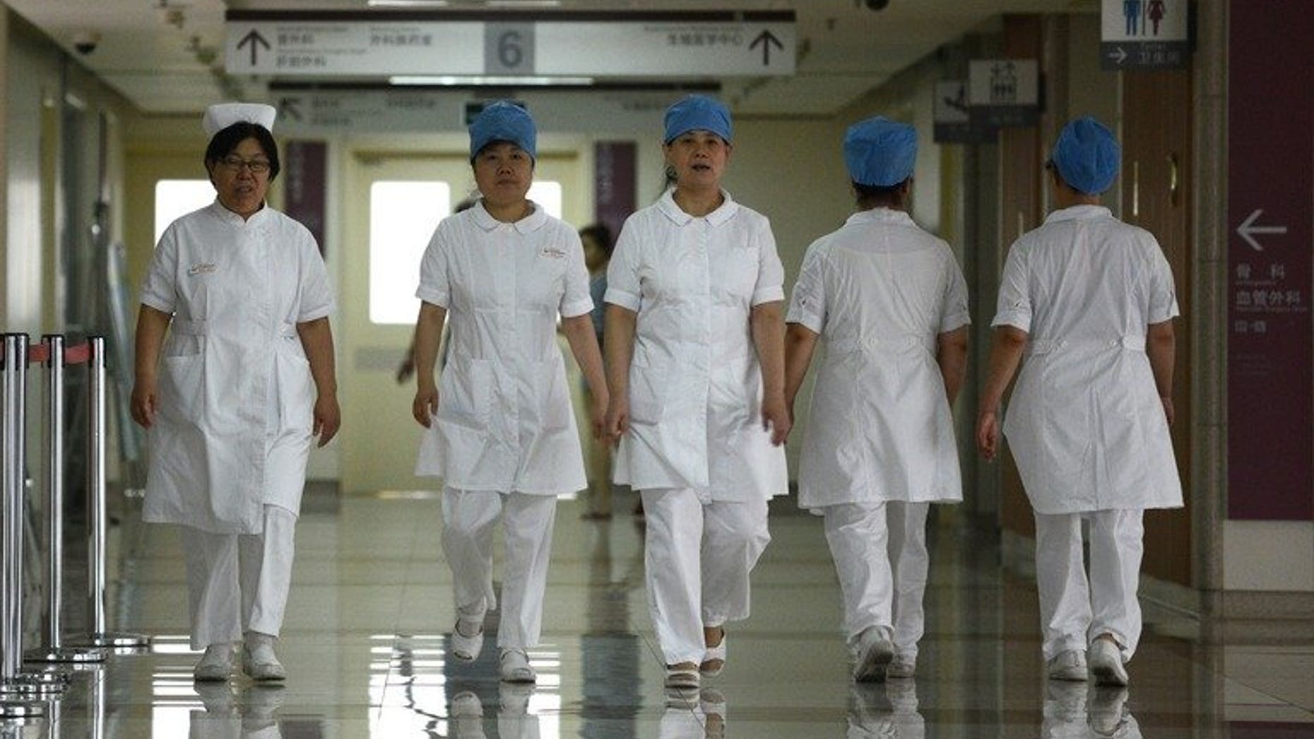 Illustration: a group of nurses walks along a corridor at a hospital in Beijing on July 29, 2013.