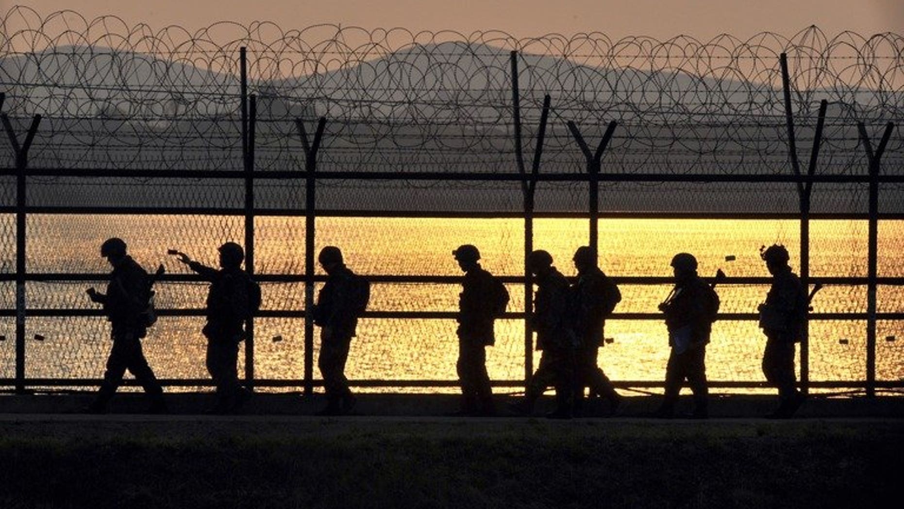 South Korean soldiers patrol along a military fence near the Demilitarized Zone (DMZ) dividing the Korean peninsula near the border city of Paju, on April 26, 2013. South Korean troops have fatally shot a man trying to swim across a border river into North Korea on Monday, after he ignored warnings, a defence ministry spokesman told AFP.