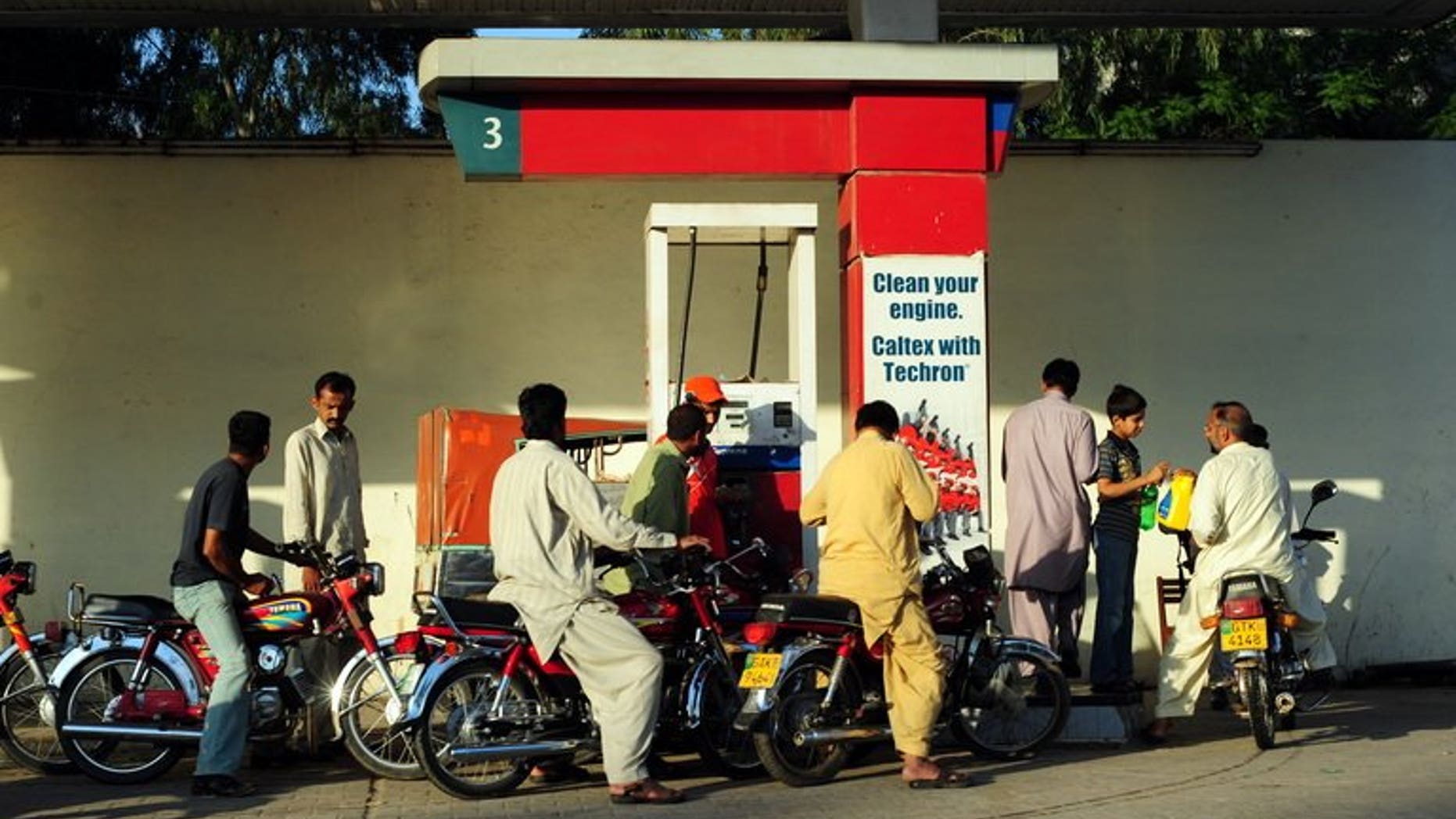 Pakistani motorcyclists gather around an oil filling point at a petrol station in Gujrat on April 15, 2011. French energy giant Total and its Pakistani partner PARCO said Wednesday they had reached a deal with American oil major Chevron to buy its fuel distribution network in Pakistan.