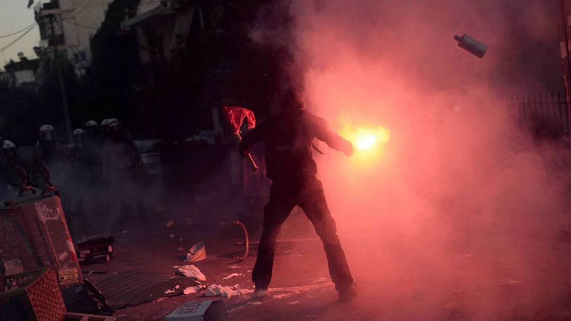 A Greek protester lights a flare during clashes with riot policemen in Athens on September 18, 2013.