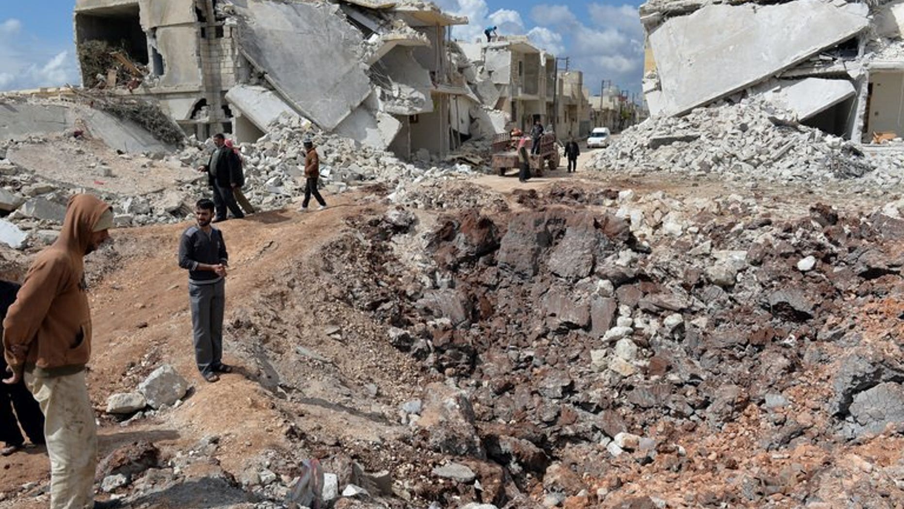 People walk past destroyed houses in the northern Syrian town of Azaz on April 21, 2013.