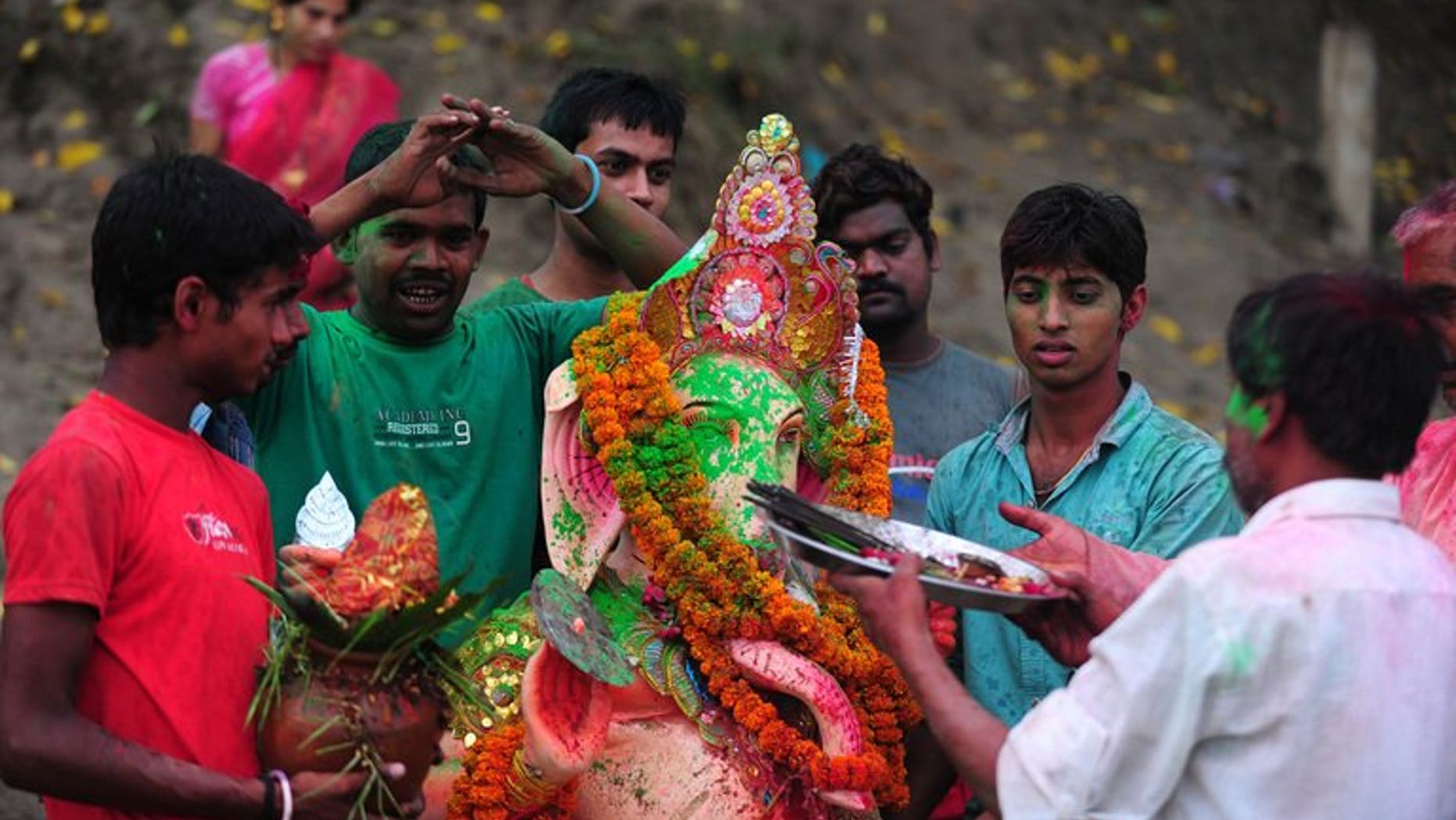 Indian devotees prepare to dip a statue of the Hindu god Ganesha in the confluence of the Yamuna and Ganges river, near Allahabad on September 15, 2013. Nine people have drowned in India's capital during religious festivals that involve immersing statues of Hindu gods in a river.