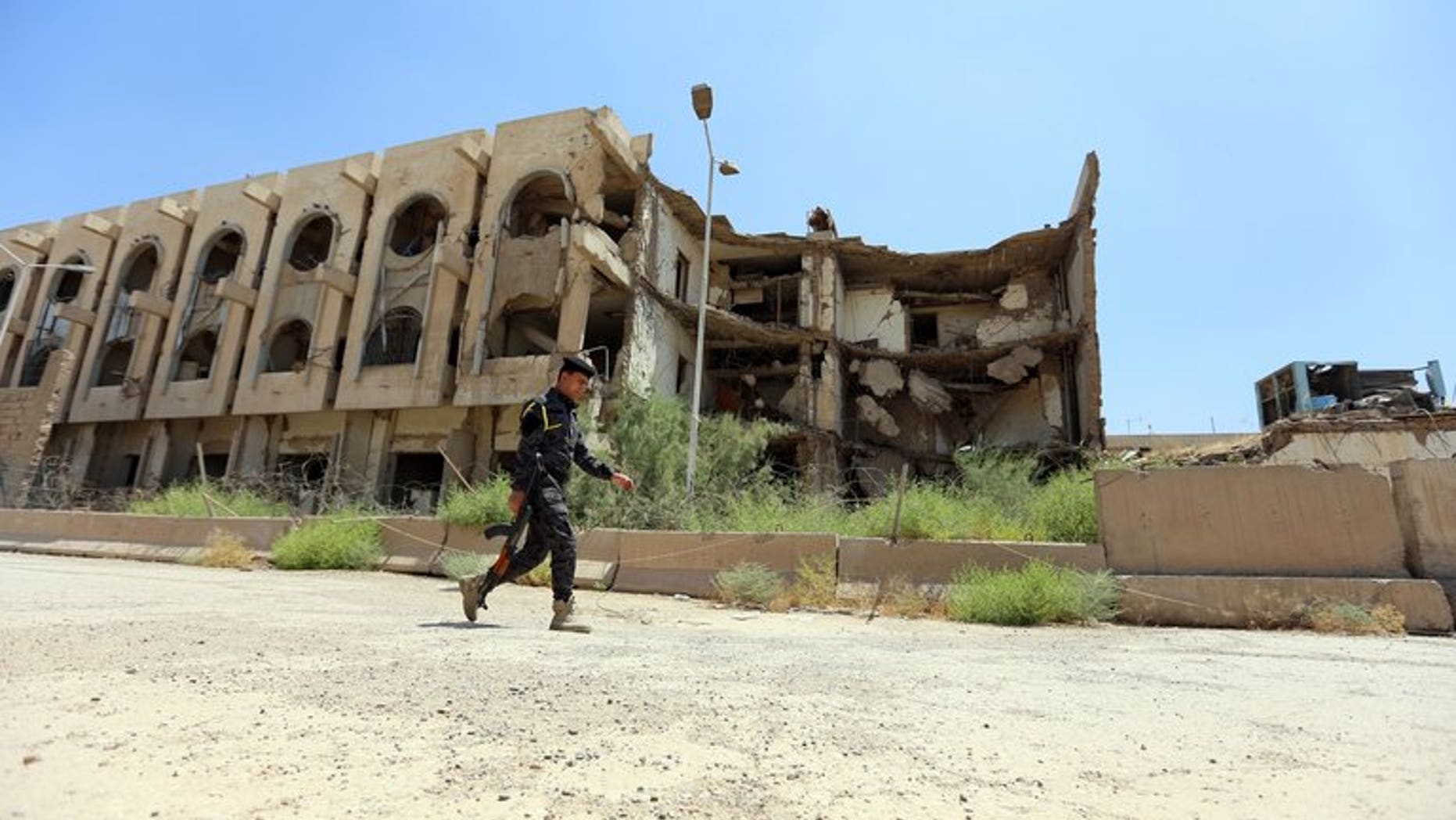 A security officer passes the destroyed former United Nations headquarters in Baghdad on August 16. The bodies of 10 young men shot in the head or chest were found on Thursday in a disused factory in the Iraqi capital, security and morgue official said.