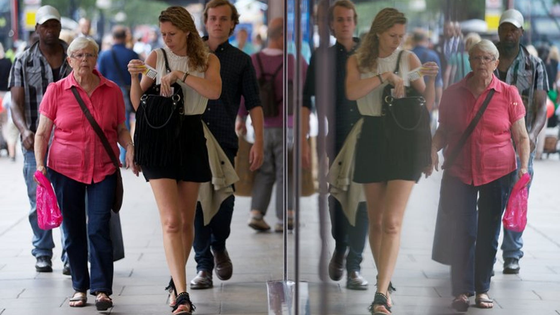 Shoppers are reflected in windows as they walk past a shop on Oxford Street in London on August 7, 2013. British retail sales fell unexpectedly in August after unusually hot weather in July had fuelled spending on food, drinks and summer clothing, official data has shown.