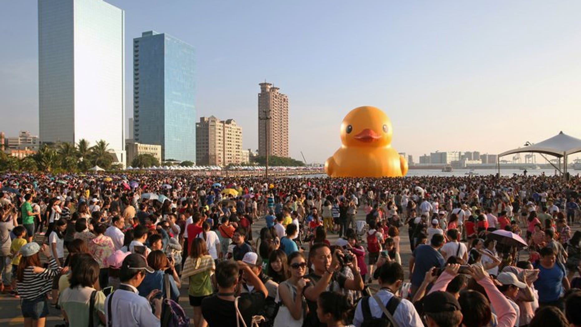 Local residents gather to see Dutch artist Florentijn Hofman's yellow rubber duck at a harbour in the Taiwanese city of Kaohsiung on September 19, 2013. A Dutch artist's now-famous giant yellow duck found a new temporary home Thursday, this time in Taiwan, but an approaching typhoon could ruffle the inflatable's feathers.