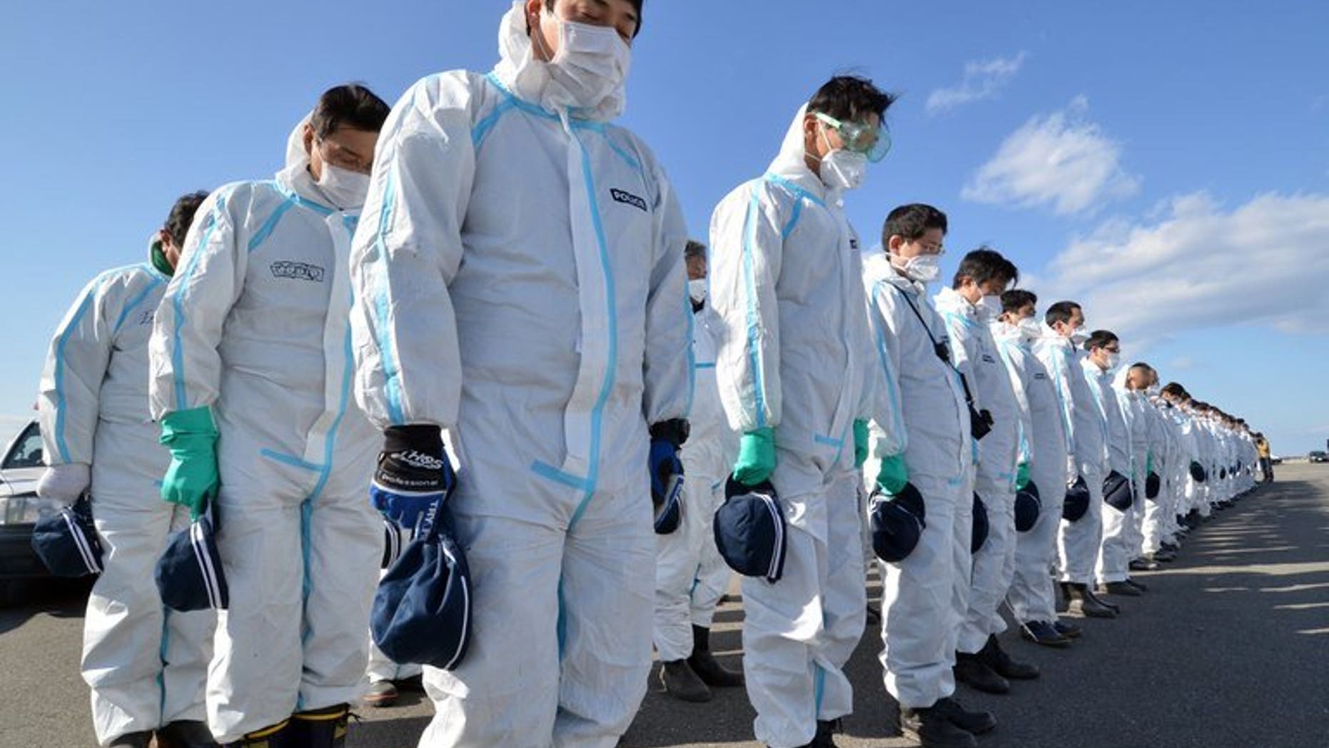 Police officers in radiation protection suits bow their heads to offer prayers in silence for tsunami victims in Namie, near the striken TEPCO's Fukushima Dai-ichi nuclear plant in Fukushima prefecture on March 11, 2013. A magnitude 5.3 earthquake rocked Japan's Fukushima prefecture early Friday morning, US seismologists said, but no tsunami warning was issued.