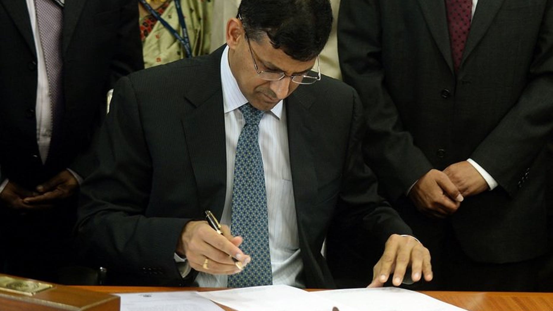 Reserve Bank of India's (RBI) newly appointed governor Raghuram Rajan signs official papers during the hand over ceremony at the RBI headquarters in Mumbai on September 4, 2013.