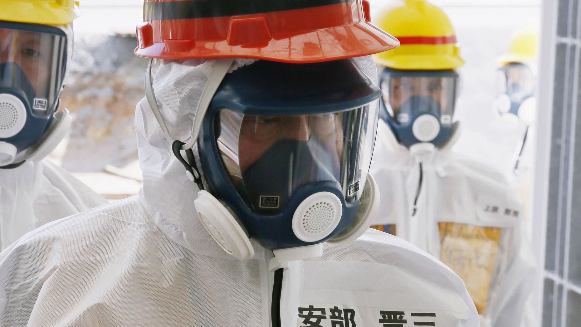 Japanese Prime Minister Shinzo Abe (C) visits the tsunami-crippled Fukushima nuclear power plant in Okuma on September 19, 2013. Red-faced officials have issued an embarrassed apology to Abe after spelling his name wrong on his protection suit, seen here.