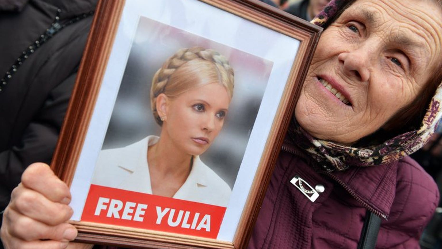 A protester holds a framed photo of jailled Ukrainian former prime minister Yulia Tymoshenko during an opposition rally in front of the central election commission in Kiev on November 6, 2012.
