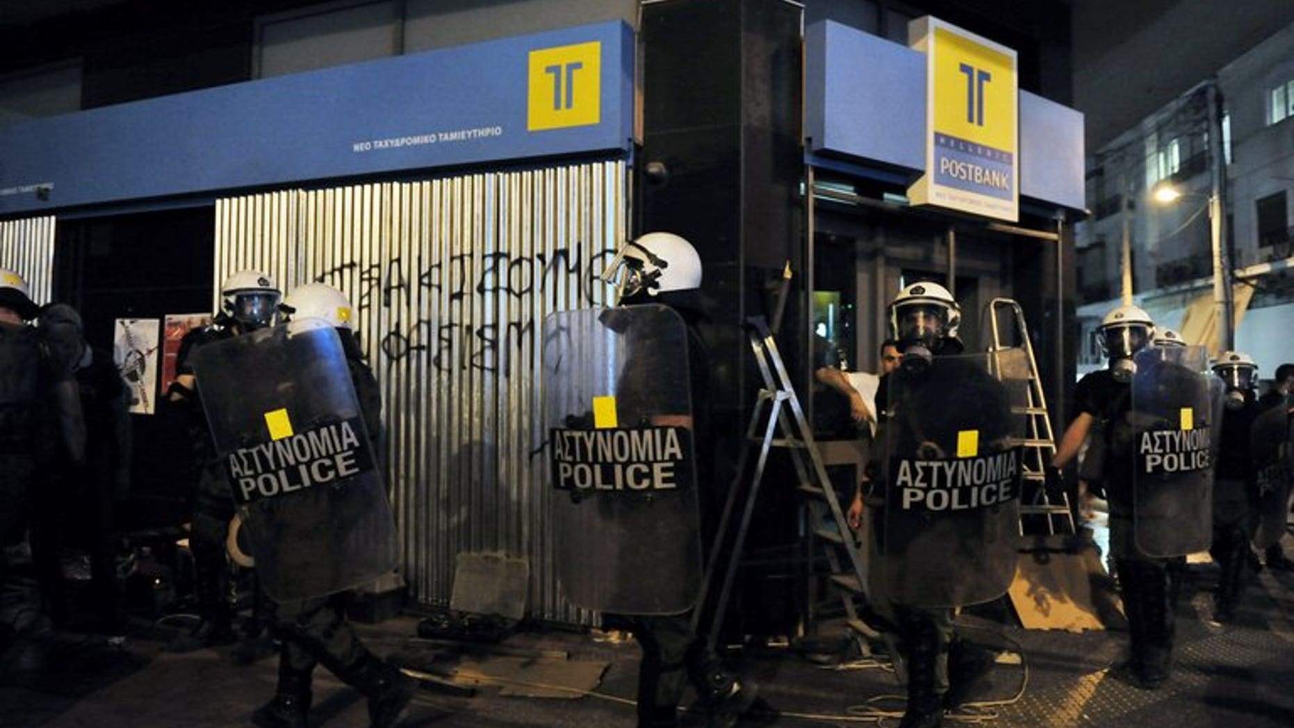 Greek riot police pass a graffiti slogan reading 'smash fascism' during a demonstration against fascism and Neo-Nazis in an Athens suburb, on September 19, 2013. The suspected killer of an anti-fascist musician, whose stabbing sparked nationwide protests and raised social tensions in the debt-wracked country, has appeared in a Piraeus courthouse under heavy security.
