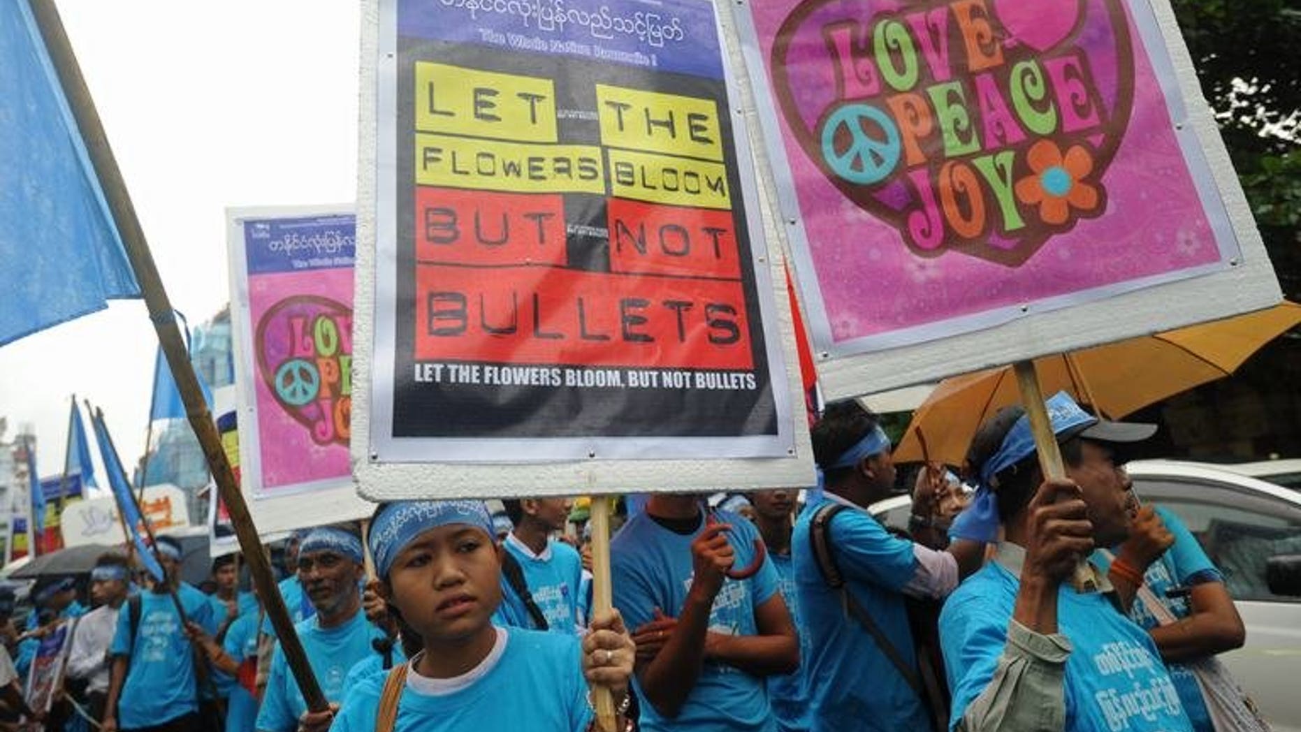 Myanmar activists hold placards as they march through Yangon, on September 21, 2013. Activists have praised Myanmar authorities for allowing a peace march through Yangon calling for an end to the nation's civil conflicts, after several people were charged for rallying without permission last year.
