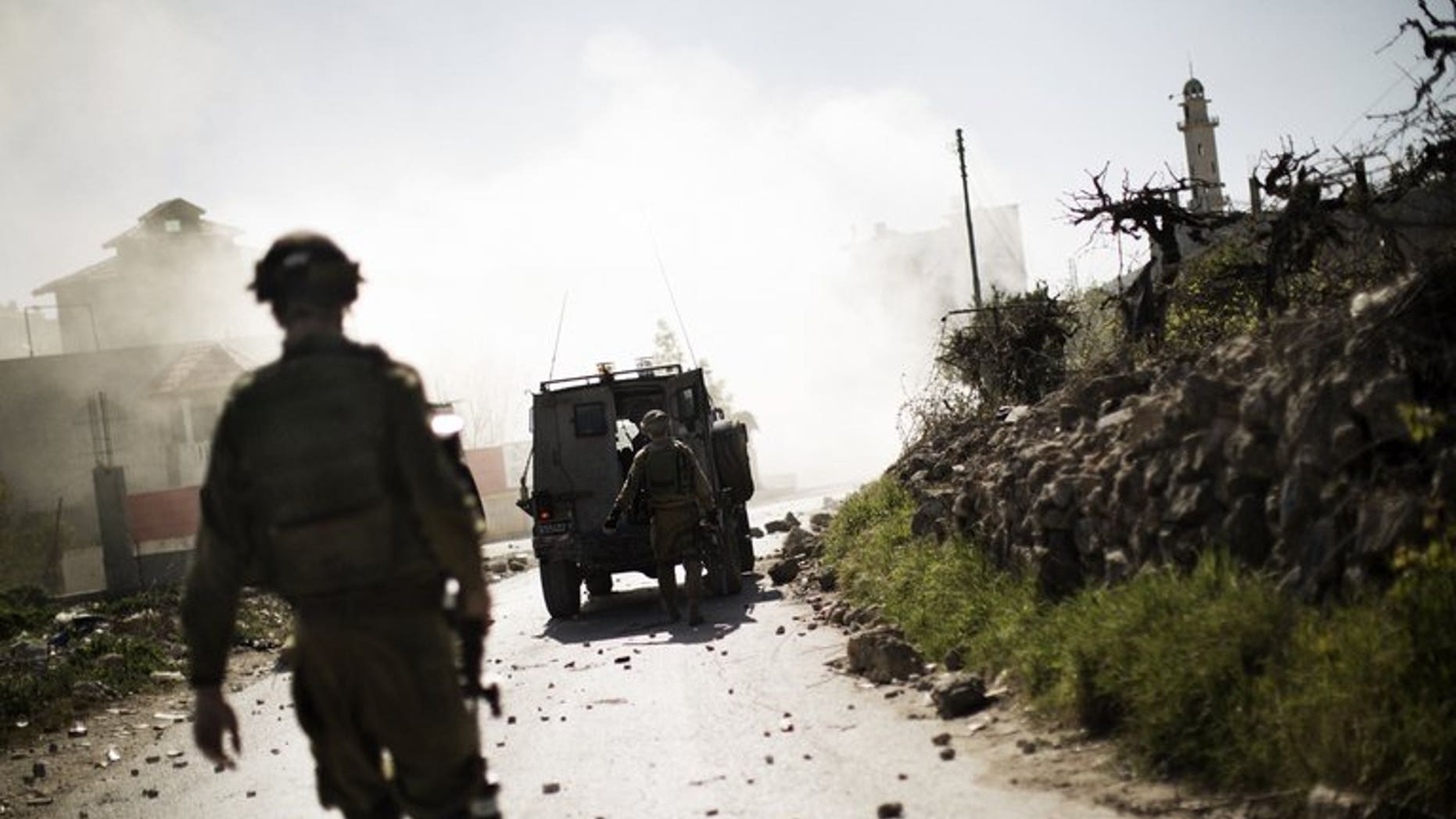 Israeli soldiers walk toward a cloud of tear gas during clashes with Palestinian stone throwers near the West Bank city of Hebron, on April 3, 2013. A Palestinian has abducted and killed an Israeli soldier whose body was found in the north of the occupied West Bank, according to the military.